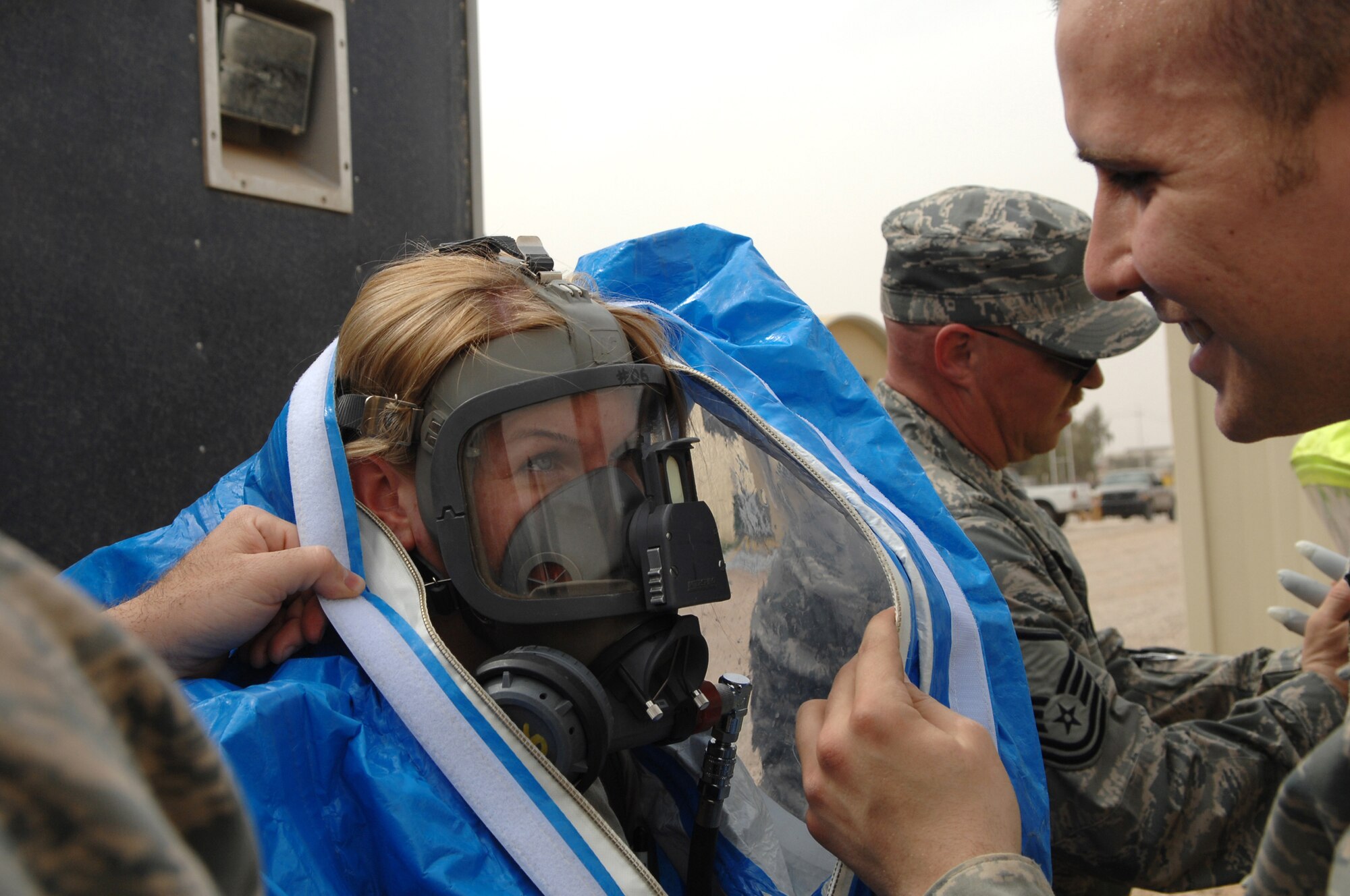 BALAD AIR BASE, Iraq -- Airman 1st Class Nathan Milliman, 332nd Expeditionary Civil Engineer Squadron emergency manager, helps Senior Airman Krista McVicar, 332 ECES emergency manager, put on a protection suit before responding to a mysterious substance report during a battle drill here, March 26. The suits can be worn for up to an hour; Airmen must work diligently to ensure they don?t become exhausted or too warm wearing the suits. The suits provide emergency managers with protection from chemical, biological, radiological or nuclear substances. Airman McVicar is deployed from Davis-Monthan Air Force Base, Ariz. (U.S. Air Force photo/ Senior Airman Julianne Showalter)