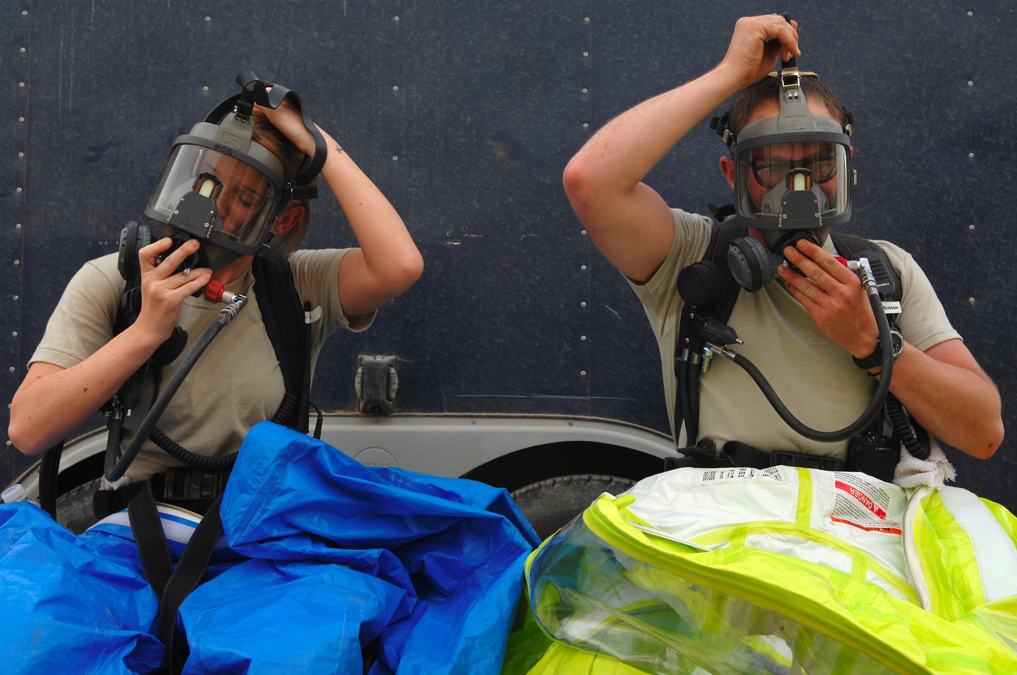 BALAD AIR BASE, Iraq -- Senior Airmen Krista McVicar and Michael Blair, 332nd Expeditionary Civil Engineer Squadron emergency managers, put on oxygen masks in preparation for a battle drill here, March 26. The battle drill required emergency managers to identify an unknown substance while employing the procedures needed to secure an area. Airman McVicar is deployed from Davis-Monthan Air Force Base, Ariz.; Airman Blair is deployed from McGuire Air Force Base, N.J. (U.S. Air Force photo/ Senior Airman Julianne Showalter)