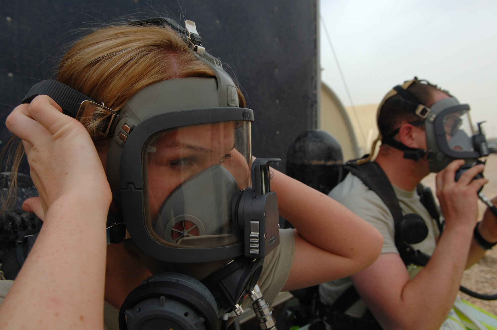 BALAD AIR BASE, Iraq -- Senior Airman Krista McVicar, 332nd Expeditionary Civil Engineer Squadron emergency manager, practices tightening her oxygen mask here, March 26. Emergency managers breathe through oxygen masks and wear protection suits that will protect them from chemical, biological, radiological or nuclear substances that may be present during a real-world attack. Emergency management Airmen conduct battle drills to keep their skills sharp and to ensure they are familiar with wearing all the required gear. Airman McVicar is deployed from Davis-Monthan Air Force Base, Ariz. (U.S. Air Force photo/ Senior Airman Julianne Showalter)