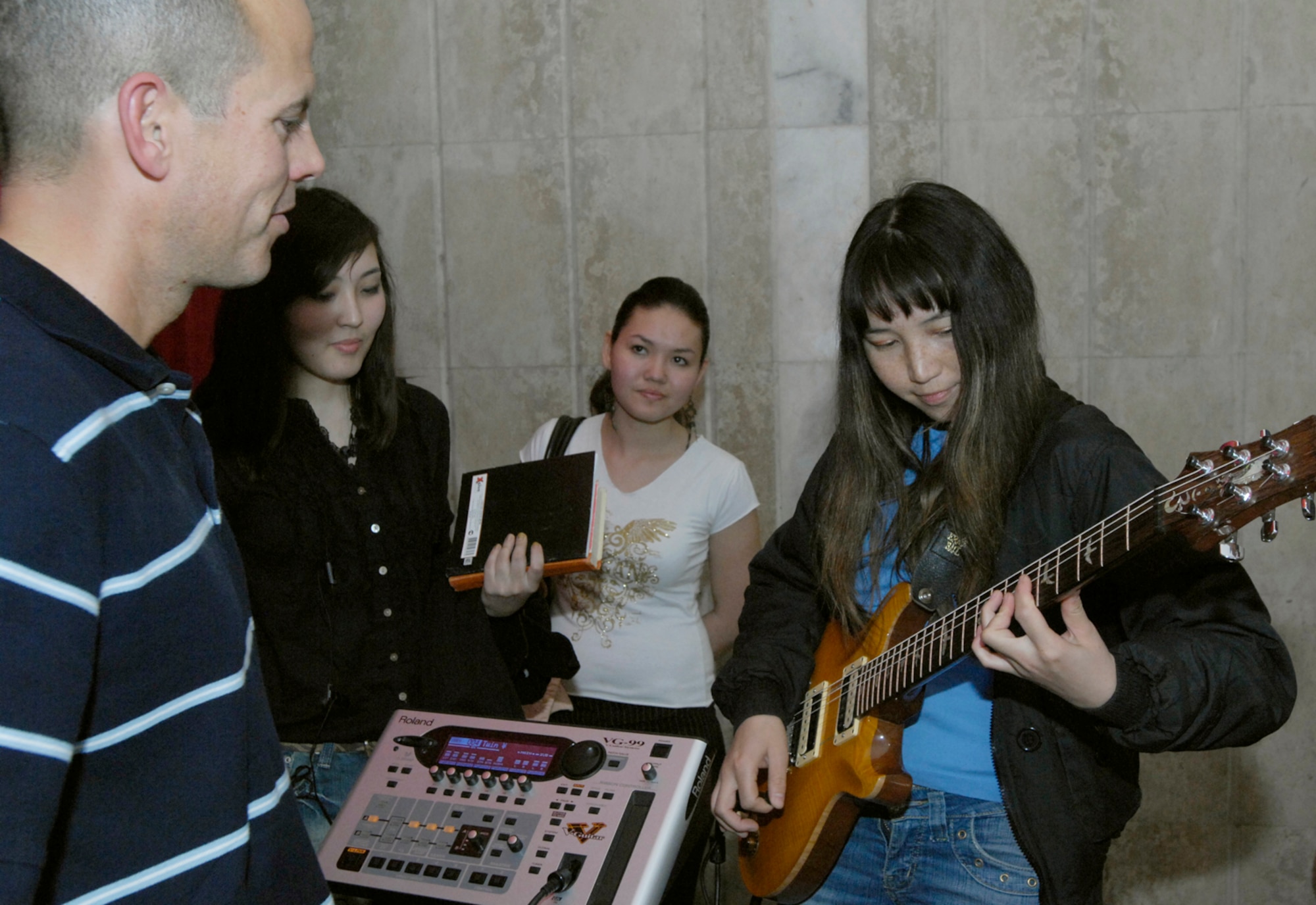 Technical Sergeant Jerry Kelley, a guitar player with the U.S. Air Force Central Band "Hot Brass," shares his instrument with Gulia Aidaralieva, a student of the Bishkek College of Music in Kyrgyzstan on March 26, 2008.  Gulia also volunteered to perform with the band during one of the songs played at the concert. The USAF pop band performed at the Bishkek College of Music as well other locations off-base during their six-day trip to Kyrgyzstan. (Air Force photo by Senior Airman Tabitha Kuykendall) 