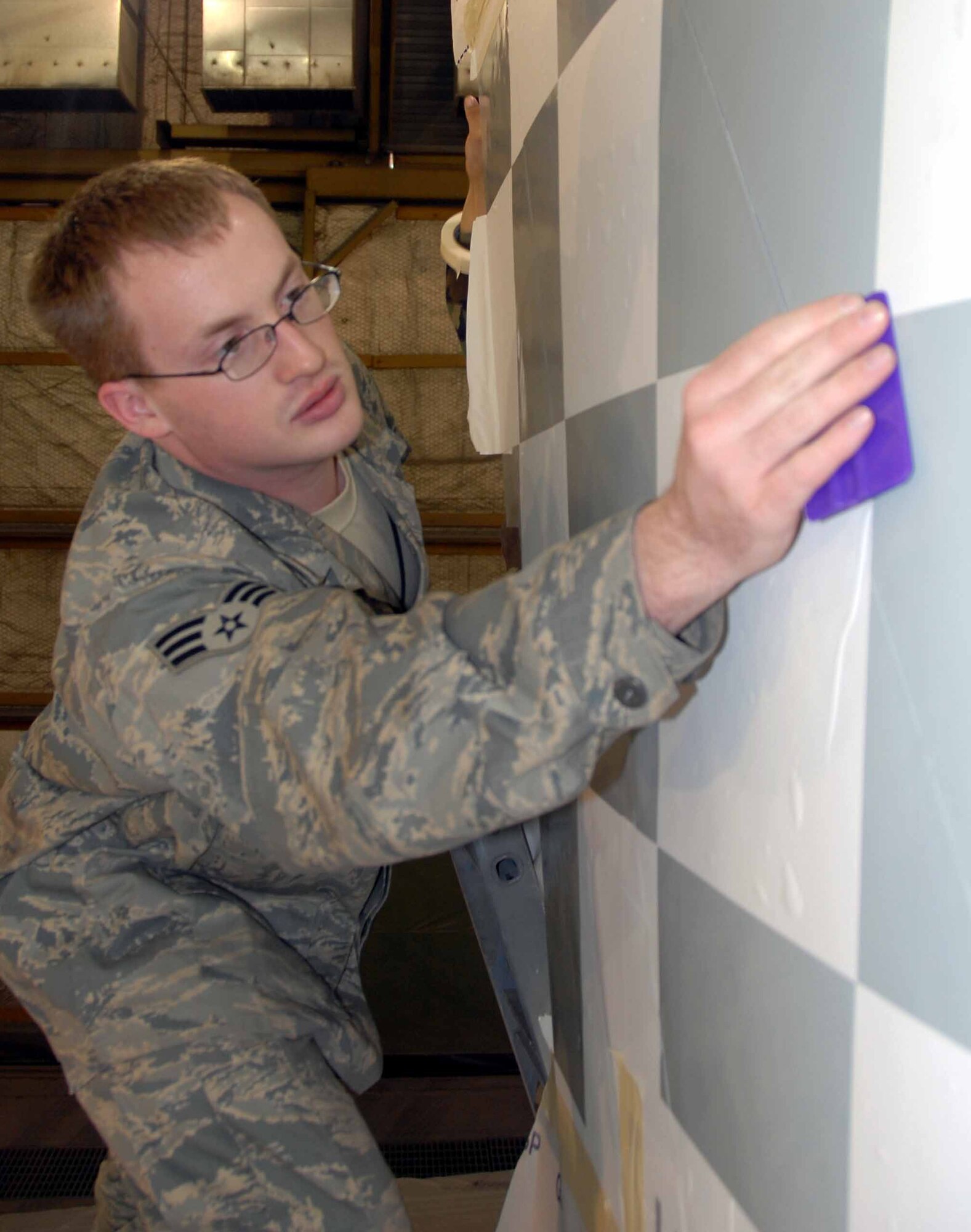 OSAN AIR BASE, Republic of Korea -- Senior Airman Paul Cotrill, 51st Maintenance Squadron aircraft structural technician, prepares Osan's historic F-86 Sabre static display aircraft for restoration and a new "checkertail" paint scheme.  The project began by removing years of weathered paint, coatings and distinctive markings entailing more than 100 man-hours of dedicated work. (U.S. Air Force photo/Senior Master Sgt. Marvin Krause)