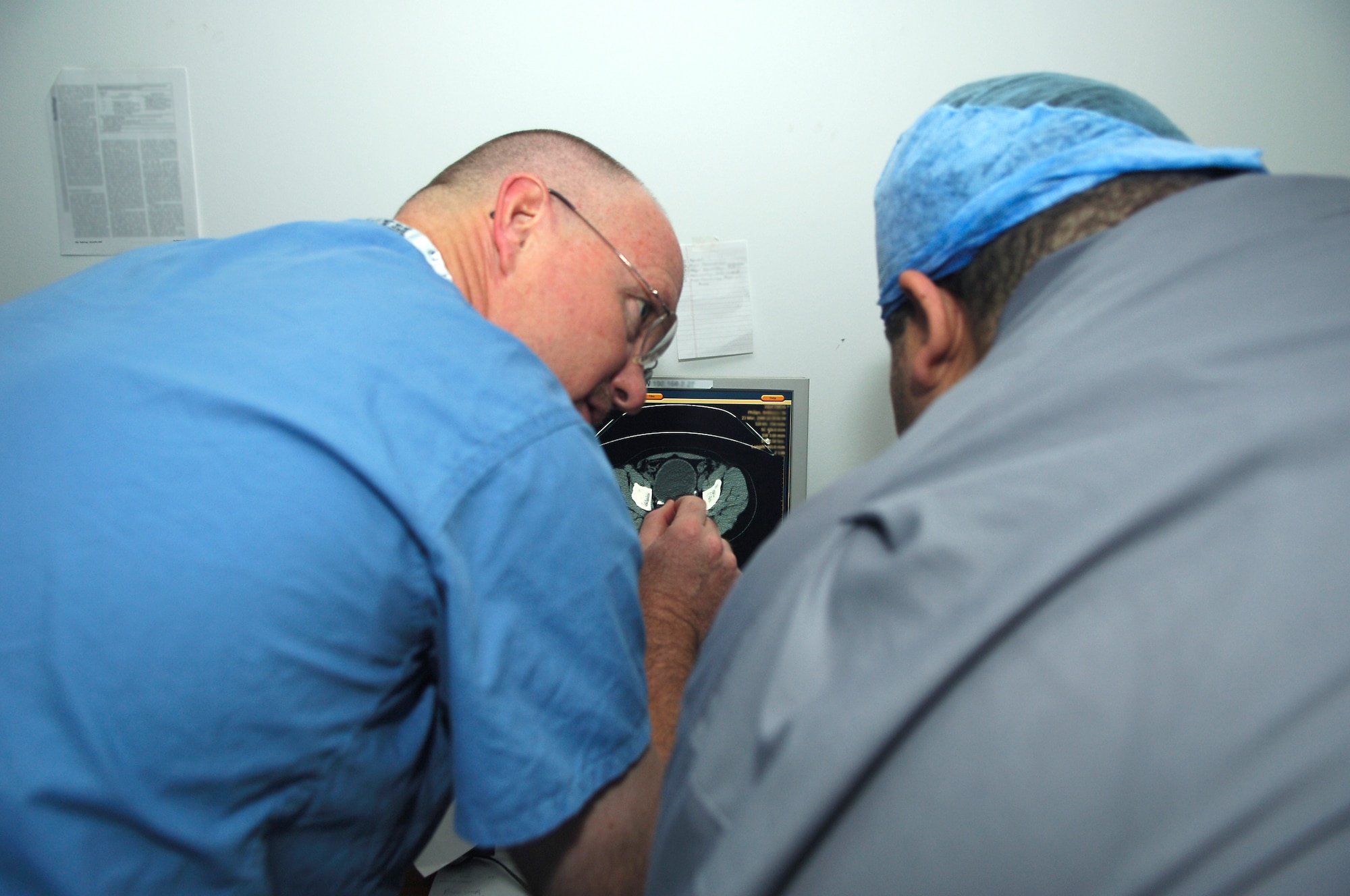 BALAD AIR BASE, Iraq -- Lt. Col. (Dr.) John Mansfield, 332nd Expeditionary Medical Operations Squadron urologist, discusses a patient's CT scan, with an Iraqi surgeon from Balad General Hospital, before going into the operating room here, March 26. The Iraqi doctor visited the Air Force Theater Hospital in conjunction with the Joint Theater Trauma System conference held here March 24 and 25 to increase the interoperability of armed forces medical treatment facilities as well as civilian hospitals in theater. Doctor Mansfield is deployed from Royal Air Force Lakenheath, England. (U.S. Air Force photo / Staff Sgt. Mareshah Haynes)
