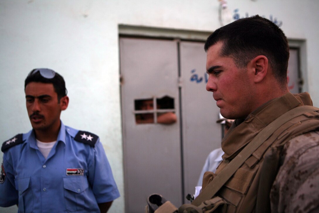 Second Lt. Mike A. Jevons, 24, an infantry officer from Manhattan, Kan., assigned to 3rd Battalion, 4th Marine Regiment, Regimental Combat Team 5, speaks with Iraqi policemen about recent activity in Hit. Marines took a tour of the Iraqi Police station, which included the holding facilities of criminals. Marines and policemen discussed conducting patrols together in the near future.
