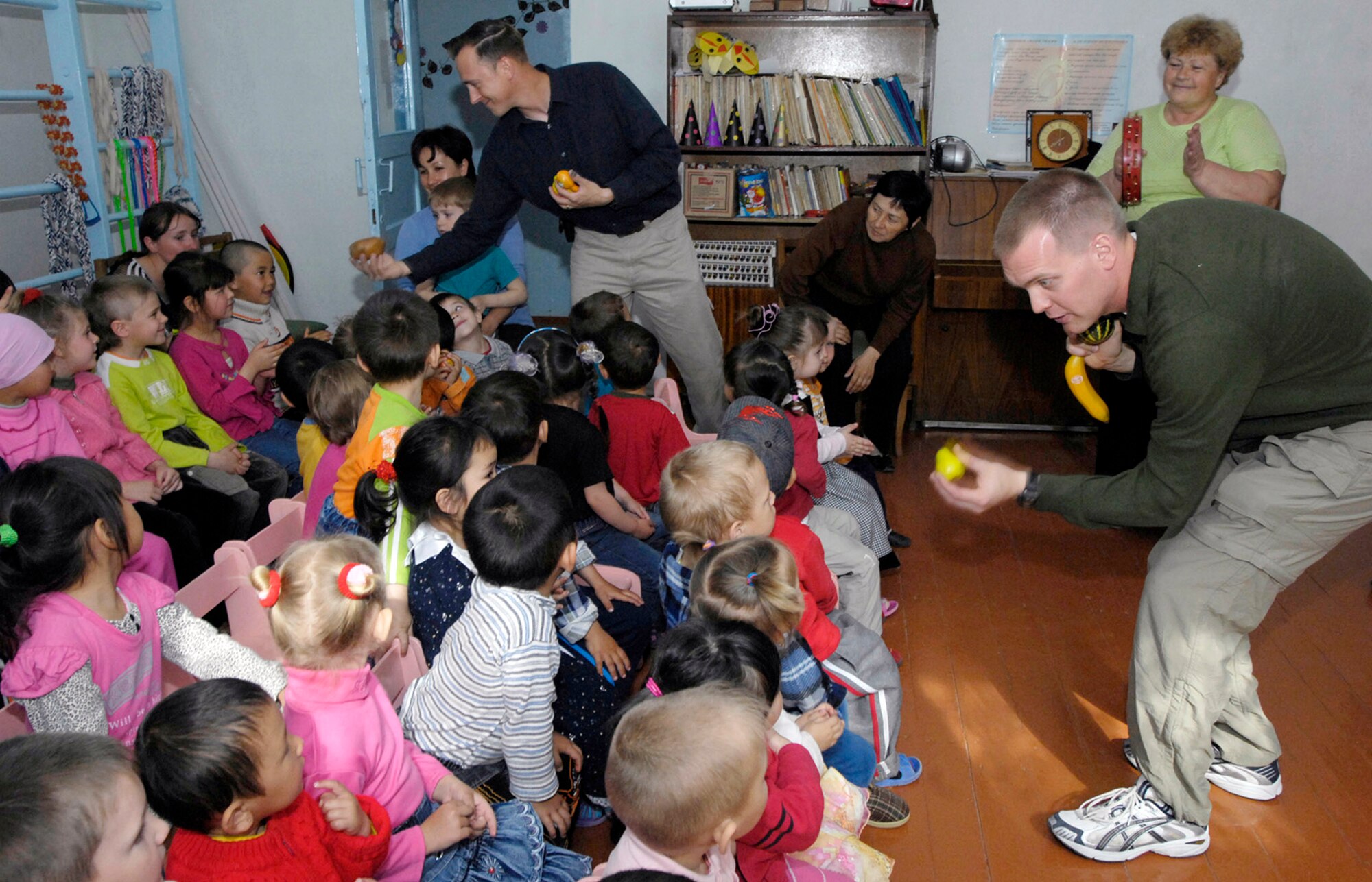 Staff Sgt. Peter Dahlstrom and Master Sgt. Rick Thorp hand out fruits and vegetables the students March 26 at the village school in Vasilievka, Kyrgyzstan. U.S. Air Forces Central Band Hot Brass members performed for Manas Air Base Airmen and local villages and schools during their six-day Kyrgyzstan tour of the U.S. Central Command area of responsibility. (U.S. Air Force photo/Senior Airman Tabitha Kuykendall) 
