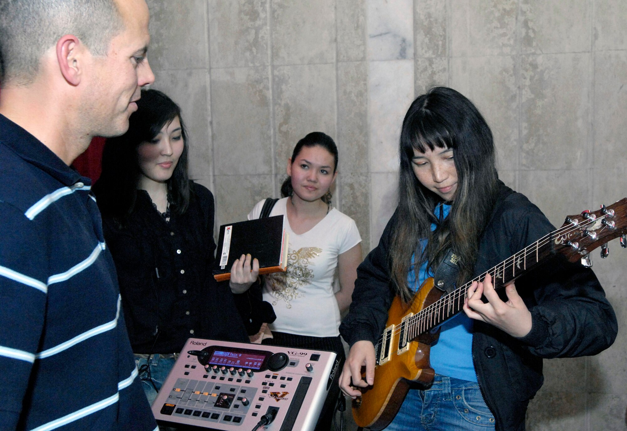 Tech. Sgt. Jerry Kelley shares his guitar with Gulia Aidaralieva March 26 at the Bishkek College of Music in Kyrgyzstan. The Air Force pop band performed at the Bishkek College of Music as well other locations off-base during their six-day trip to Kyrgyzstan. Sergeant Kelley is a guitar player with the U.S. Air Forces Central Band Hot Brass. Miss Aidaralieva is a student of the Bishkek College of Music in Kyrgyzstan. (U.S. Air Force photo/Senior Airman Tabitha Kuykendall) 

