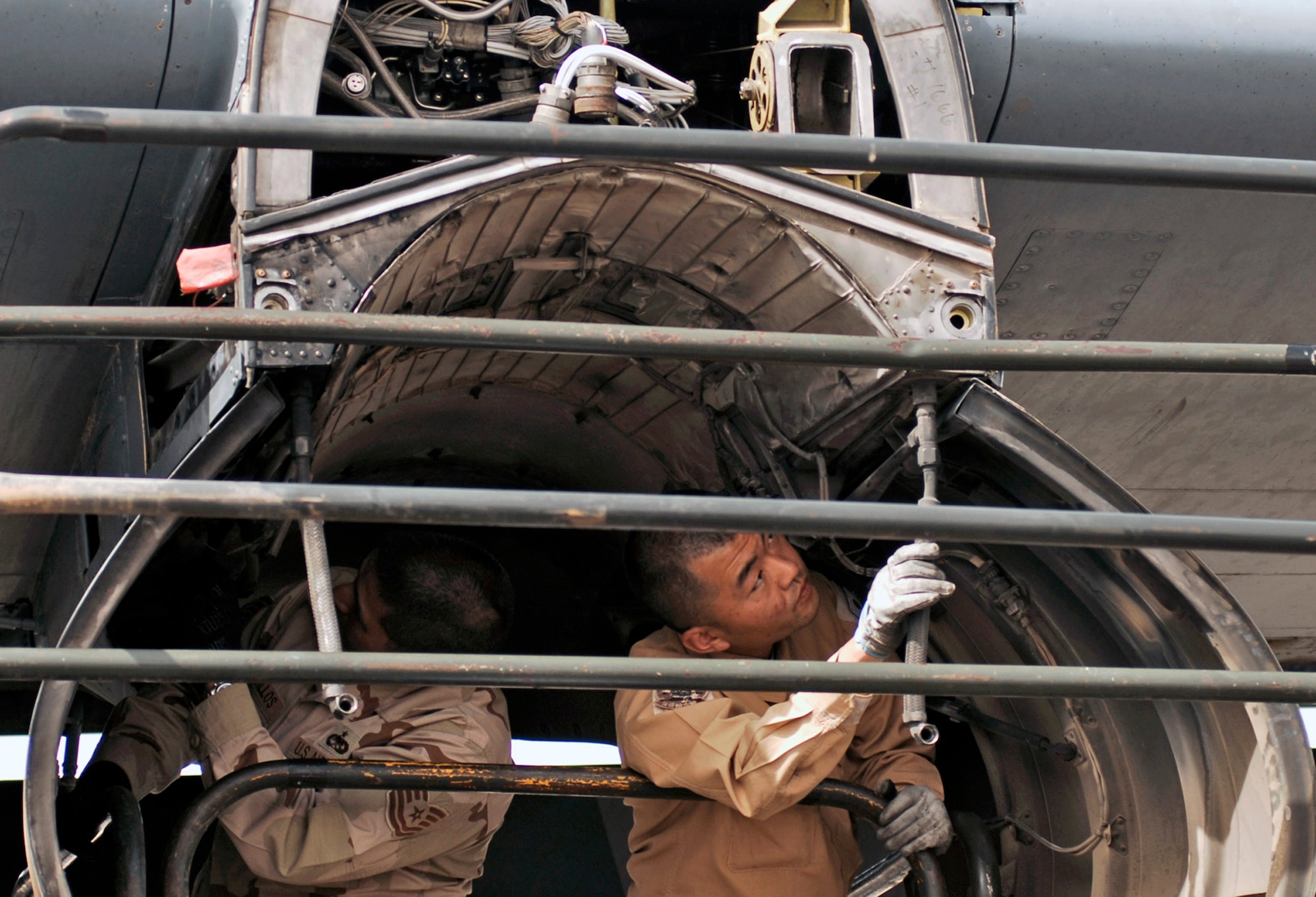 Tech. Sgt. Porfirio Bustillos (left) and Staff Sgt. Kouichi Tsunoda inspect an engine insulation blanket for cracks, holes and deterioration on a C-130 Hercules March 21 at a Southwest Asian air base. Airmen from the U.S., Japanese Air Self-Defense Force and South Korean air force's 58th Airlift Wing participated in a coalition maintenance exchange program allowing maintainers to sharpen their skills, exchange ideas, and promote closer relations among coalition air forces supporting the war on terrorism. Sergeant Bustillos is a maintainer deployed to the 386th Expeditionary Aircraft Maintenance Squadron, and Sergeant Tsunoda is a maintainer from the Japan Air Self-Defense Force Iraq Reconstruction Support Airlift Wing. (U.S. Air Force photo/Staff Sgt. Patrick Dixon) 

