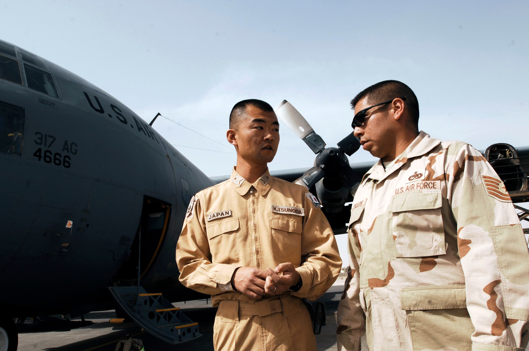 Japanese Staff Sgt. Kouichi Tsunoda (left) and Tech. Sgt. Porfirio Bustillos speak with each other before performing an inspection on an C-130 Hercules March 21 at a Southwest Asian air base. Airmen from the U.S., Japanese Air Self-Defense Force and South Korean air force's 58th Airlift Wing participated in a coalition maintenance exchange program allowing maintainers to sharpen their skills, exchange ideas, and promote closer relations among coalition air forces supporting the war on terrorism. Sergeant Tsunoda is a maintainer from the Japan Air Self-Defense Force Iraq Reconstruction Support Airlift Wing, and Sergeant Bustillos is a maintainer deployed to the 386th Expeditionary Aircraft Maintenance Squadron. (U.S. Air Force photo/Staff Sgt. Patrick Dixon) 
