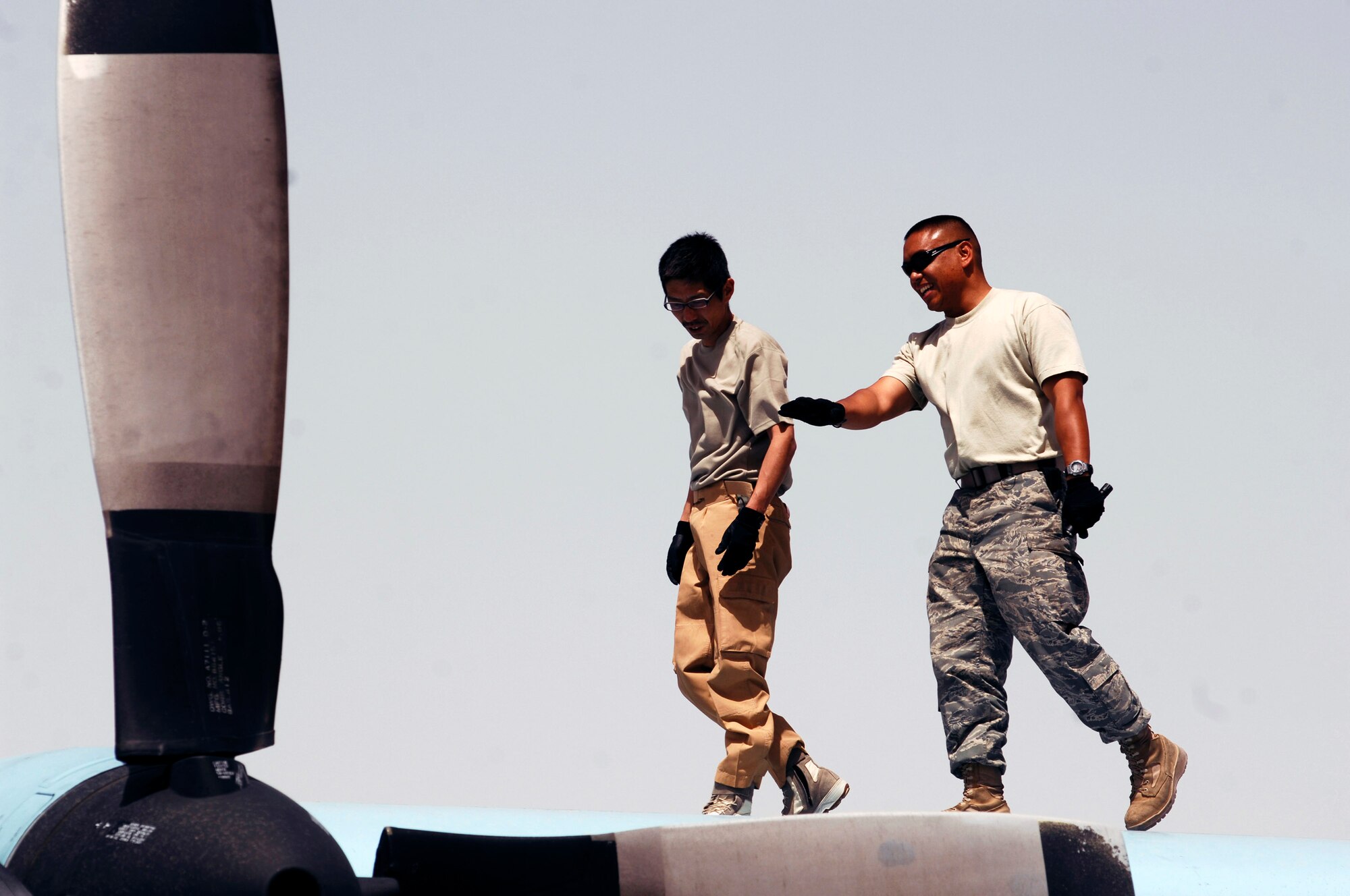 Japanese Tech. Sgt. Hidetoshi Takeuchi (left) and Staff Sgt. Ray Pontemayor walk across the wing of Japanese Air Self-Defense Force C-130 Hercules March 21 at a Southwest Asian air base. Airmen from the U.S., Japanese Air Self-Defense Force and South Korean air force's 58th Airlift Wing participated in a coalition maintenance exchange program allowing maintainers to sharpen their skills, exchange ideas, and promote closer relations among coalition air forces supporting the war on terrorism. Sergeant Takeuchi is a maintainer from the Japan Air Self-Defense Force Iraq Reconstruction Support Airlift Wing, and Sergeant Pontemayor is a maintainer deployed to the 386th Expeditionary Aircraft Maintenance Squadron. (U.S. Air Force photo/Staff Sgt. Patrick Dixon) 

