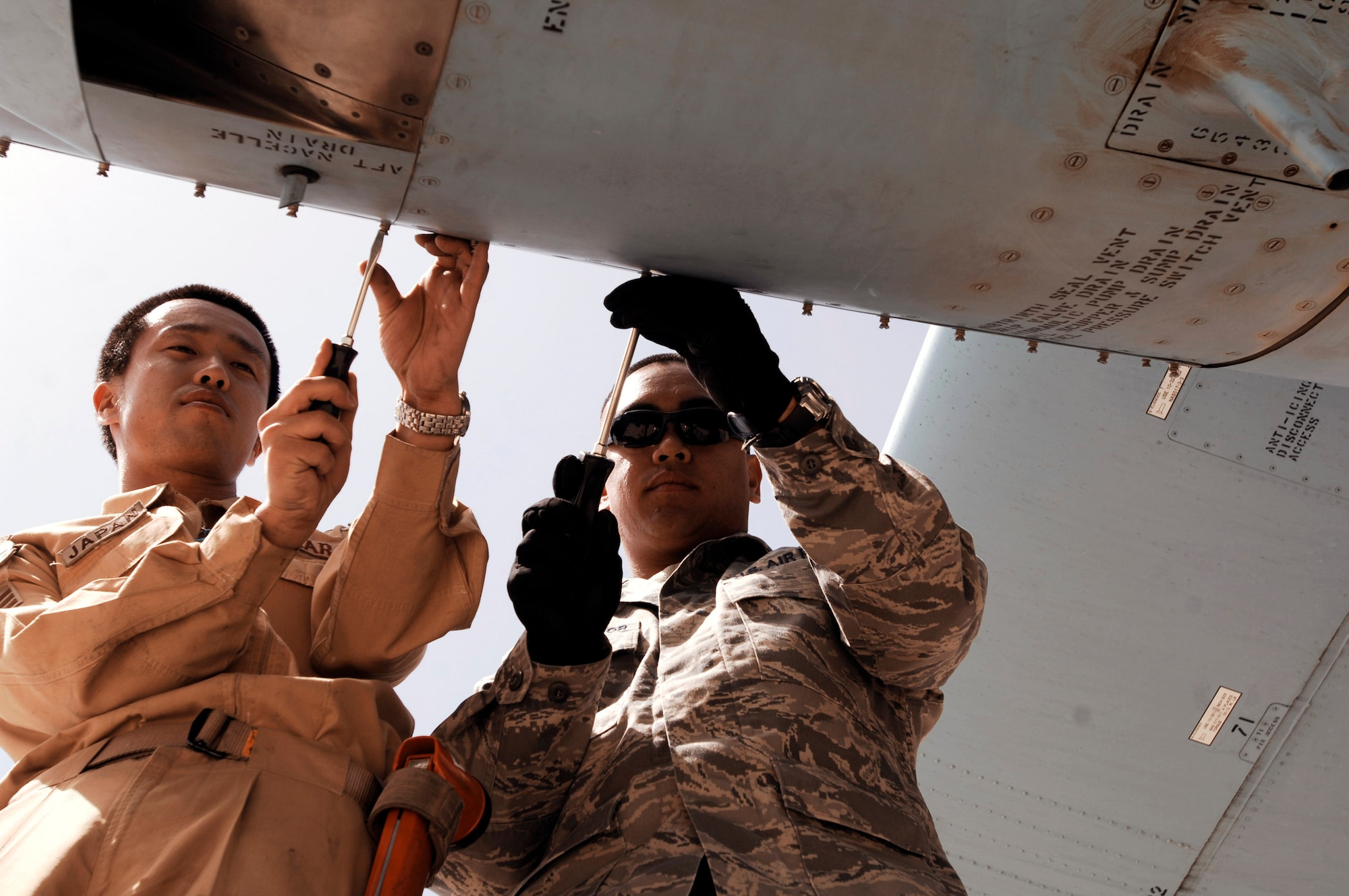 Japanese Senior Airman Yuta Kawahara (left) and Staff Sgt. Ray Pontemayor open a panel on an engine of a Japan Air Self-Defense Force C-130 Hercules March 21 at a Southwest Asian air base. Airmen from the U.S., Japan Air Self-Defense Force and South Korean air force's 58th Airlift Wing participated in a coalition maintenance exchange program allowing maintainers to sharpen their skills, exchange ideas and promote closer relations among coalition air forces supporting the war on terrorism. Airman Kawahara is a maintainer from the Japan Air Self-Defense Force Iraq Reconstruction Support Airlift Wing, and Sergeant Pontemayor is a maintainer deployed to the 386th Expeditionary Aircraft Maintenance Squadron. (U.S. Air Force photo/Staff Sgt. Patrick Dixon) 
