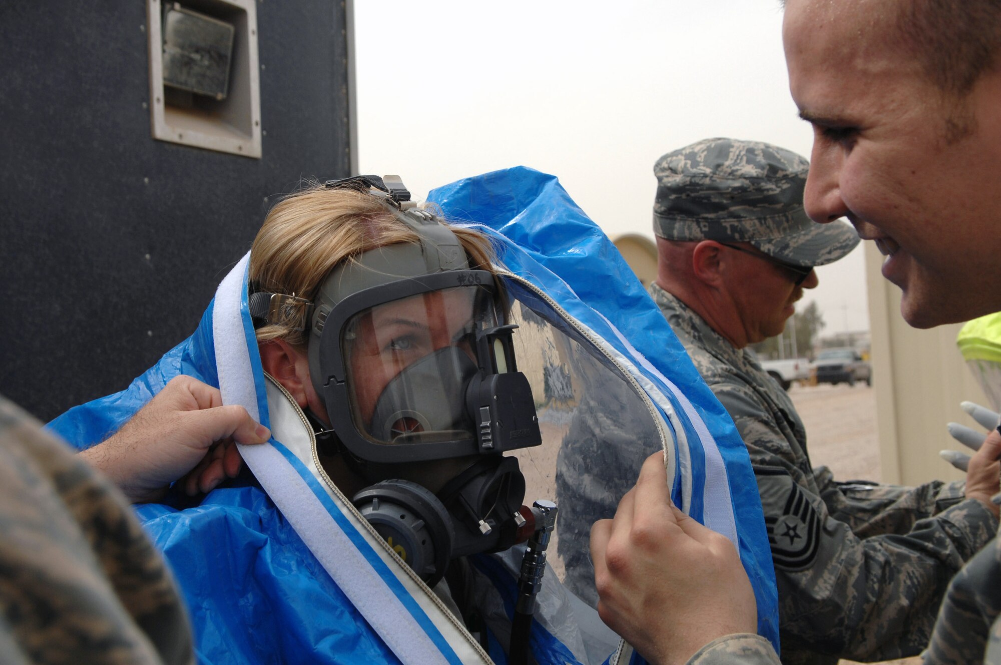 Airman 1st Class Nathan Milliman helps Senior Airman Krista McVicar put on a protection suit before responding to a mysterious substance scenerio during a battle drill March 26 at Balad Air Base, Iraq. The suits can be worn for up to one hour; Airmen must work diligently to ensure they don't become exhausted or too warm when wearing the suits. The suits provide emergency managers with protection from chemical, biological, radiological or nuclear substances. Both Airmen are 332nd Expeditionary Civil Engineer Squadron emergency managers. Airman Milliman is deployed from Hurlburt Field, Fla.; Airman McVicar is deployed from Davis-Monthan Air Force Base, Ariz. (U.S. Air Force photo/Senior Airman Julianne Showalter) 
