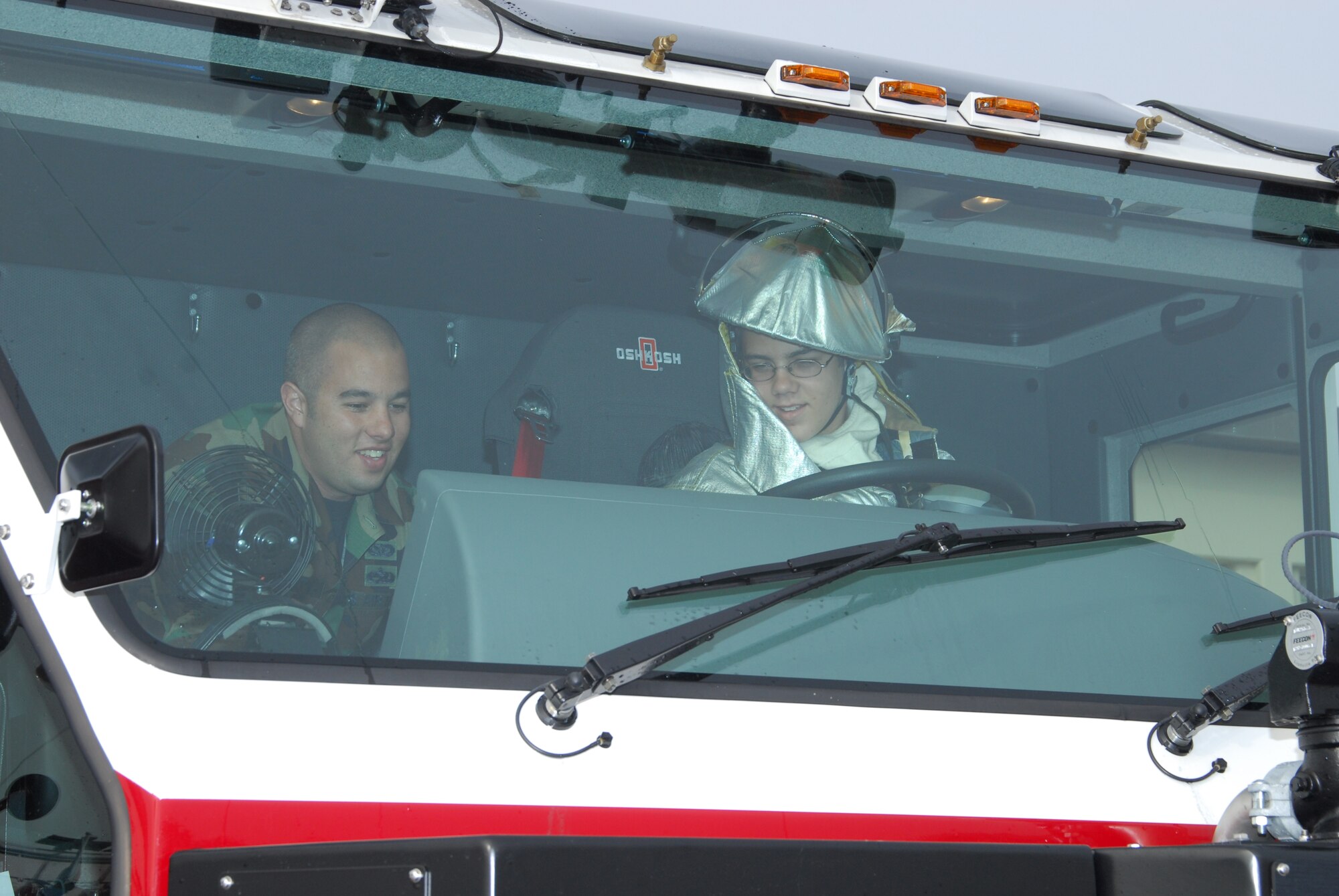 Firefighter for a Day, Austin Mayer, right, waters down Tyndall’s flightline from the driver's seat of the base's newest fire truck with the assistance of Staff Sgt. William Mavity, 325th Civil Engineer Squadron fire protection specialist, March 28. (U.S. Air Force photo by Lisa Norman)