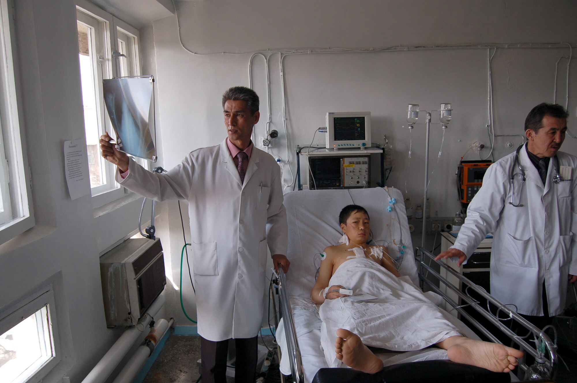 Dr. Samudin Shabyralie, heart surgeon in the local Institute of Cardiac Surgery and Organ Transplantation and Dr. Kaldarbek Abdramanov, Director and professor of surgery check on the Manas Air Base Outreach Society-sponsored 100th heart surgery patient, Alymbekov Amanbek, Saturday in the Children's Heart Ward. (Air Force photo by Tech. Sgt. Jerome Baysmore)  