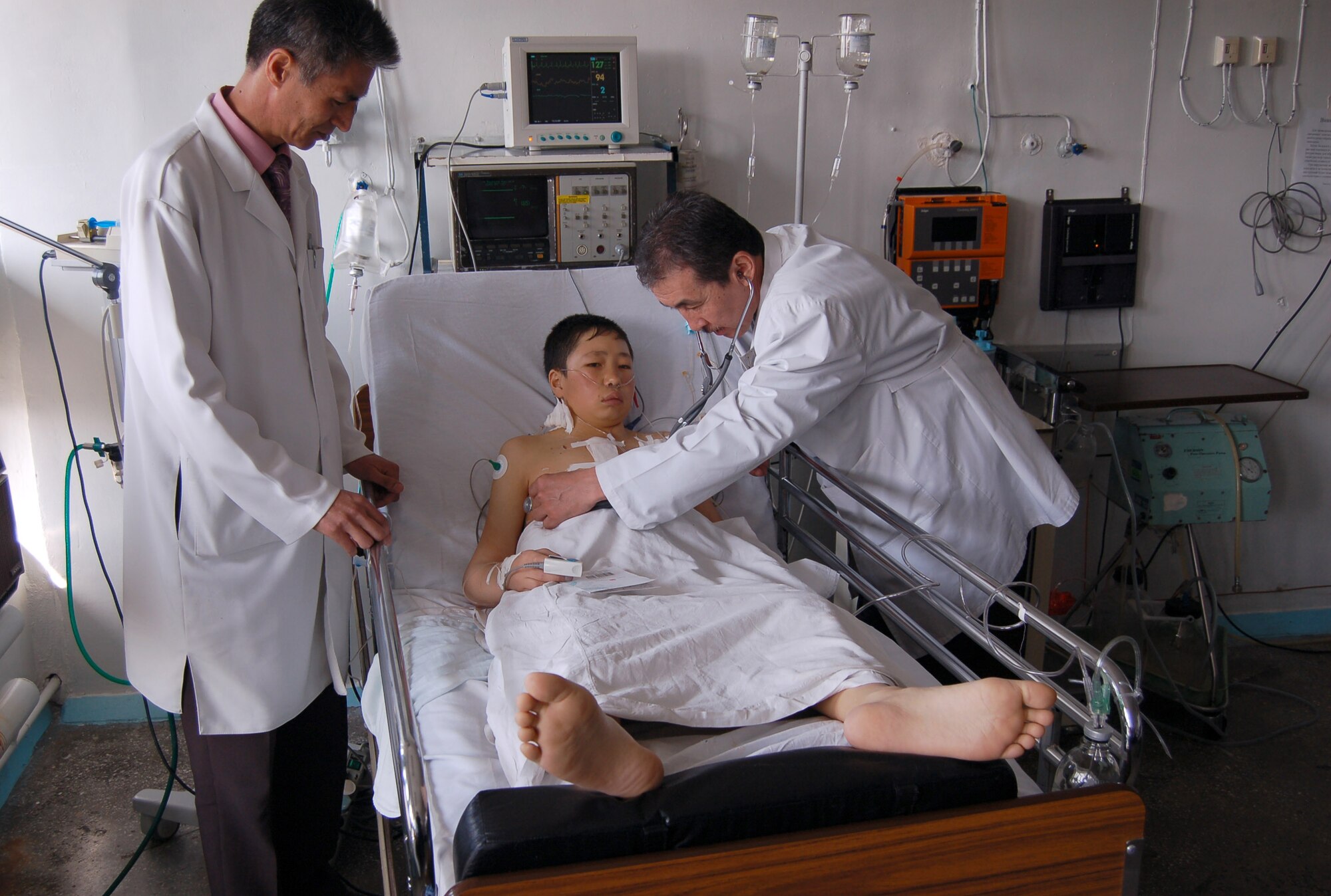 Dr. Samudin Shabyralie, heart surgeon in the local Institute of Cardiac Surgery and Organ Transplantation and Dr. Kaldarbek Abdramanov, Director and professor of surgery check on the Manas Air Base Outreach Society-sponsored 100th heart surgery patient, Alymbekov Amanbek, Saturday in the Children's Heart Ward. (Air Force photo by Tech. Sgt. Jerome Baysmore)  