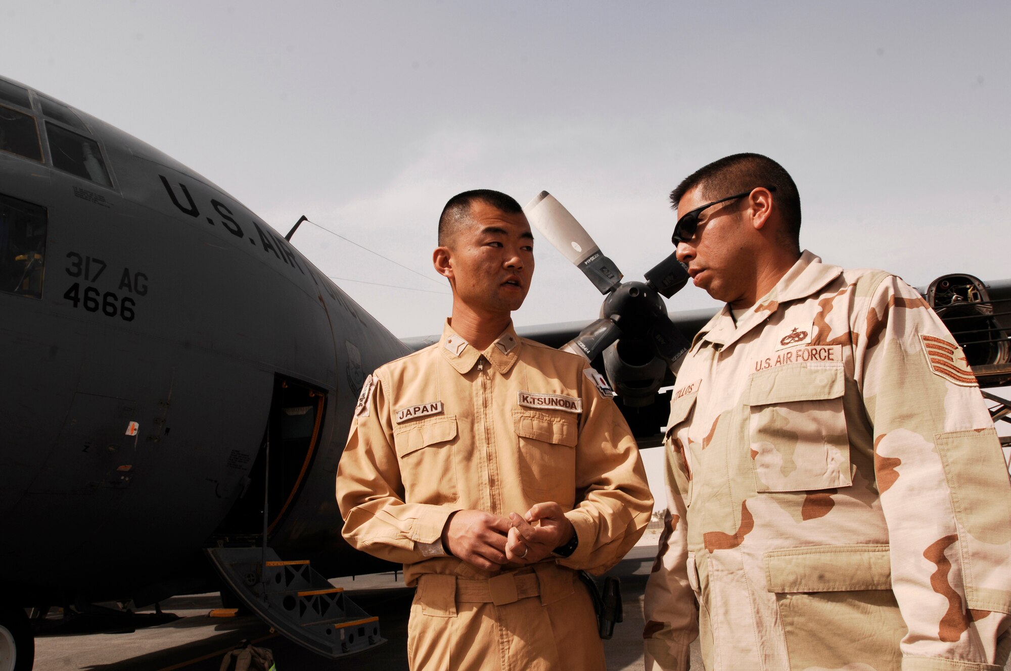 SOUTHWEST ASIA -- Staff Sergeant Kouichi Tsunoda (left), a maintainer from the Japan Air Self-Defense Force Iraq Reconstruction Support Airlift Wing and Tech. Sgt. Porfirio Bustillos, an maintainer deployed to the 386th Expeditionary Aircraft Maintenance Squadron, speak with each other before performing an inspection on an U.S. Air Force C-130 Hercules March 21, 2008, at an air base in the Persian Gulf Region. Airmen from the U.S., JASDF, and Republic of Korea Air Force 58th Airlift Wing participated in a coalition maintenance exchange program allowing maintainers to sharpen their skills, exchange ideas, and promote closer relations among coalition air forces supporting the Global War on Terrorism. (U.S. Air Force photo/ Staff Sgt. Patrick Dixon)