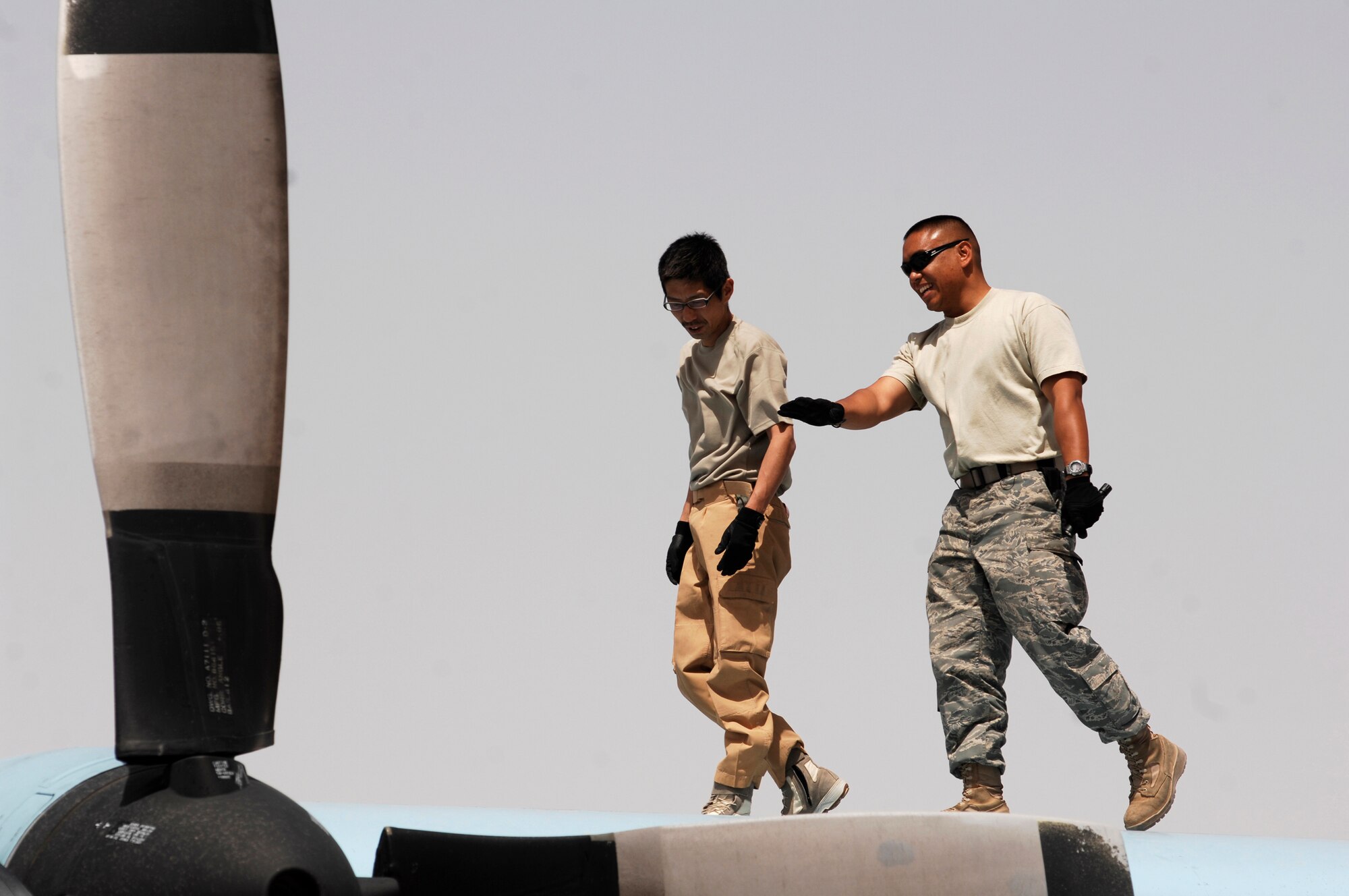 SOUTHWEST ASIA -- Technical Sergeant Hidetoshi Takeuchi (left), a maintainer from the Japan Air Self-Defense Force Iraq Reconstruction Support Airlift Wing and Staff Sgt. Ray Pontemayor (right), an aircraft maintainer deployed to the 386th Expeditionary Aircraft Maintenance Squadron, walk across the wings of JASDF C-130 Hercules March 21, 2008, at an air base in the Persian Gulf Region. Airmen from the U.S., JASDF, and Republic of Korea Air Force 58th Airlift Wing participated in a coalition maintenance exchange program allowing maintainers to sharpen their skills, exchange ideas, and promote closer relations among coalition air forces supporting the Global War on Terrorism. (U.S. Air Force photo/ Staff Sgt. Patrick Dixon)