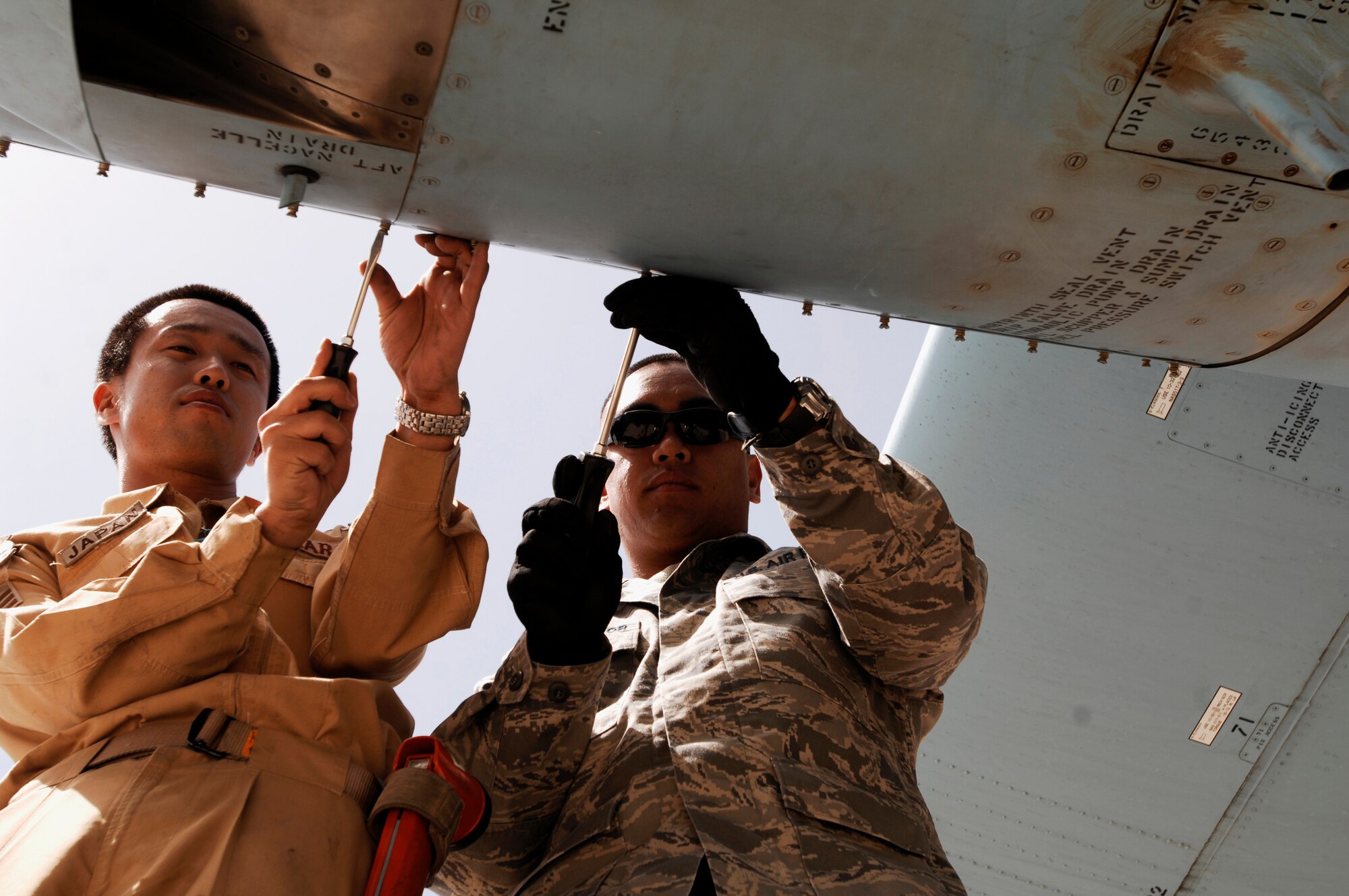 SOUTHWEST ASIA -- Senior Airman Yuta Kawahara (left), a maintainer from the Japan Air Self-Defense Force Iraq Reconstruction Support Airlift Wing and Staff Sgt. Ray Pontemayor, a maintainer deployed to the 386th Expeditionary Aircraft Maintenance Squadron, open a panel on an engine of a JASDF C-130 Hercules March 21, 2008, at an air base in the Persian Gulf Region. Airmen from the U.S., JASDF, and Republic of Korea Air Force 58th Airlift Wing participated in a coalition maintenance exchange program allowing maintainers to sharpen their skills, exchange ideas, and promote closer relations among coalition air forces supporting the Global War on Terrorism. (U.S. Air Force photo/ Staff Sgt. Patrick Dixon)