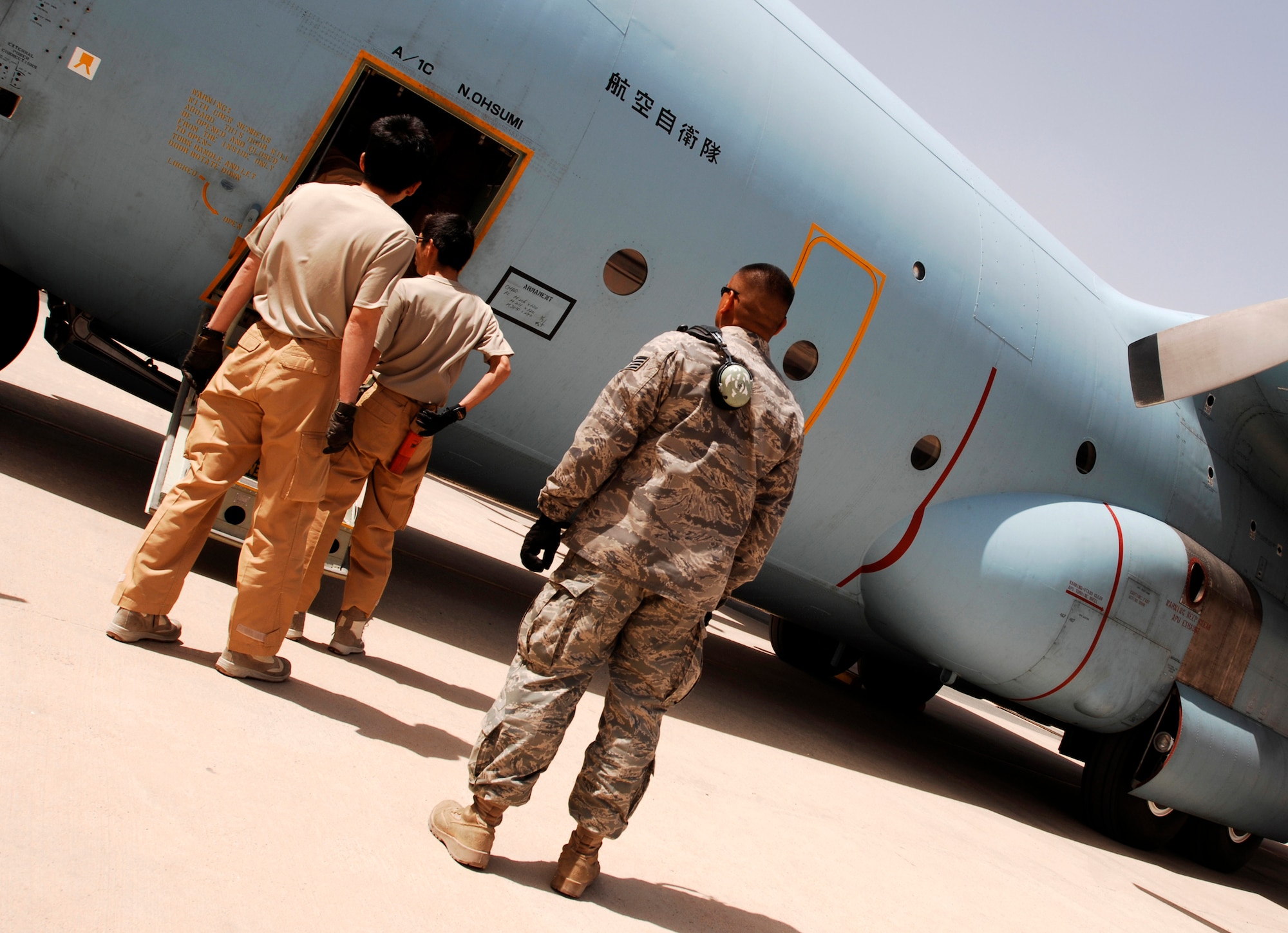 SOUTHWEST ASIA -- Staff Sgt. Ray Pontemayor (center), a maintainer deployed to the 386th Expeditionary Aircraft Maintenance Squadron, waits as personnel disembark from a Japan Air Self-Defense Force C-130 Hercules March 21, 2008, at air base in the Persian Gulf Region. Airmen from the U.S., JASDF, and Republic of Korea Air Force 58th Airlift Wing participated in a coalition maintenance exchange program allowing maintainers to sharpen their skills, exchange ideas, and promote closer relations among coalition air forces supporting the Global War on Terrorism. (U.S. Air Force photo/ Staff Sgt. Patrick Dixon)