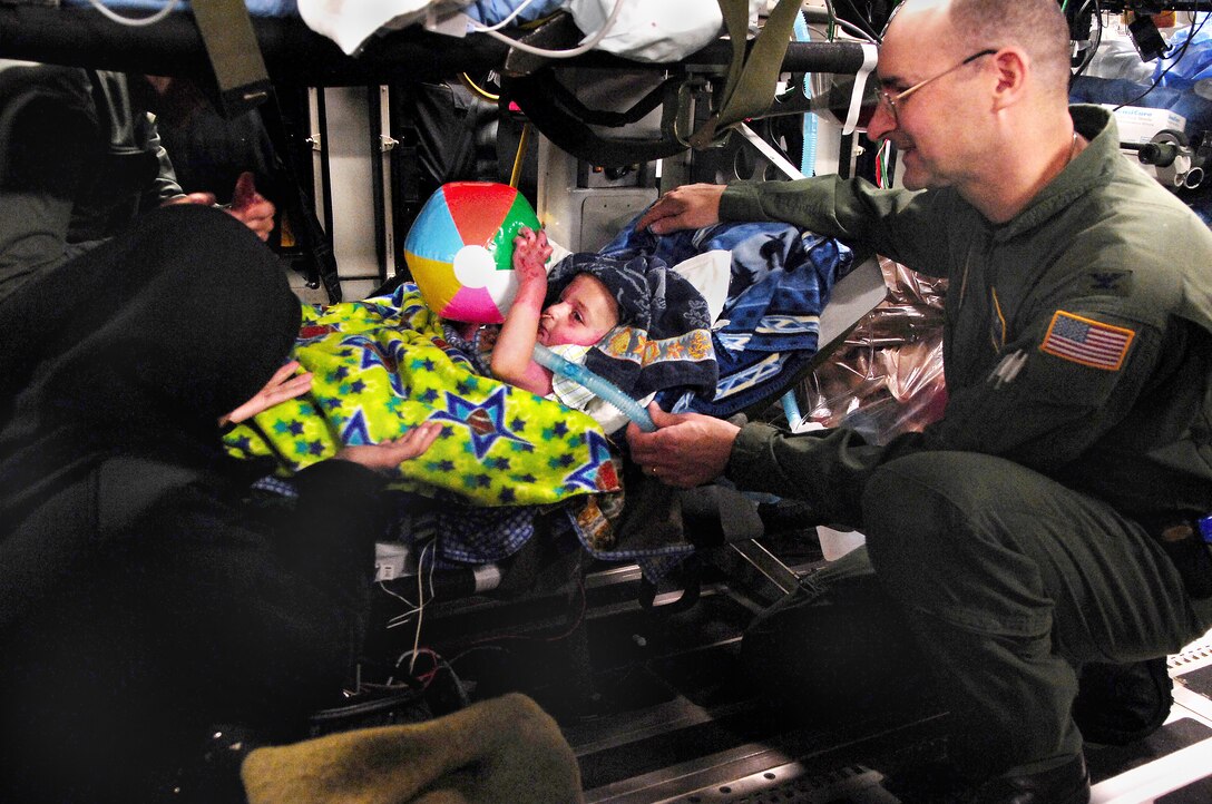 U.S. Air Force Col. William Venanzi, a doctor assigned with a critical care air transport team, 88th Medical Group, plays with a three-year-old Iraqi burn victim on board a C-17 Globemaster III aircraft during a medical evacuation flight to the United States from Ramstein Air Base, Germany, March 21, 2008. 