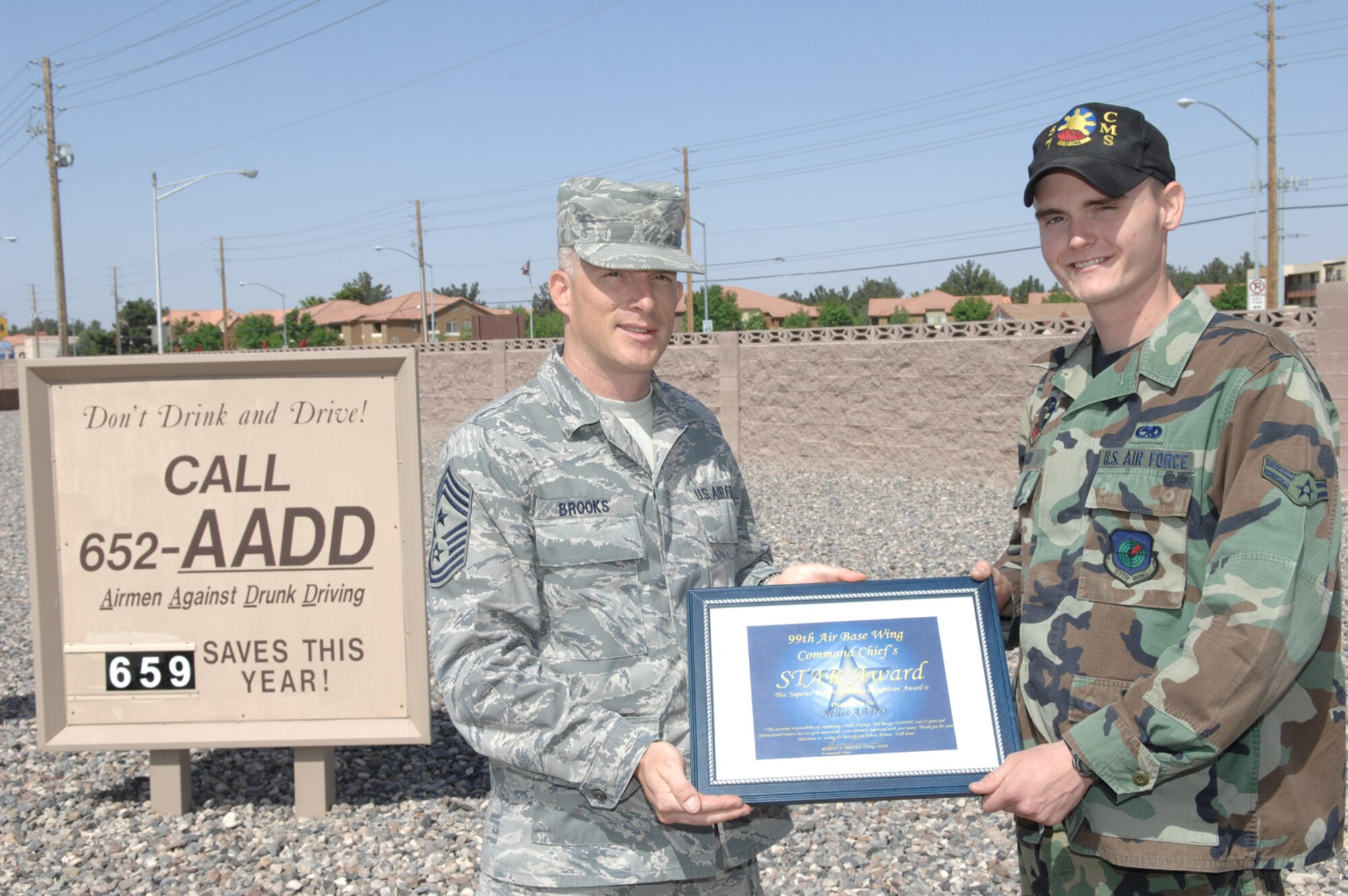 NELLIS AIR FORCE BASE, Nev.--Airman 1st Class Justin Ward, Airmen Against Drunk Driving council secretary, receives the Command Chief’s STAR Award from 99th Air Base Wing Command Chief Master Sgt. Robert Brooks, during an informal ceremony at the main gate here, April 30. Airman Ward accepted the award on the behalf of the AADD council and all the volunteer Airmen who’ve pledged their time to ensure the safety of countless Nellis Airmen. (U.S. Air Force photo/Senior Airman Larry E. Reid Jr.)
