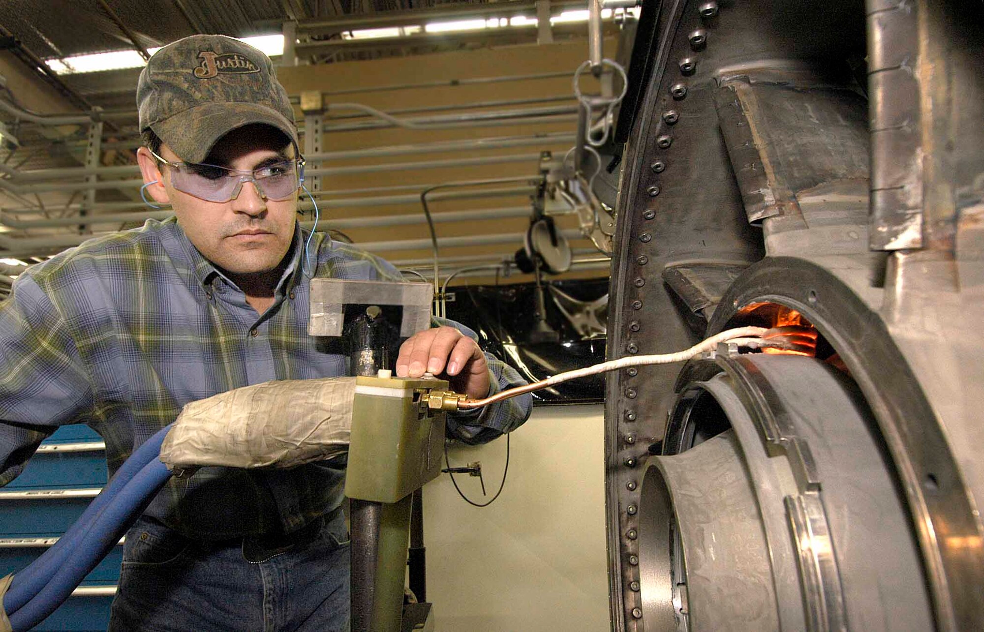 When a process cost time and money yet yielded only a seven percent success rate, a team of Tinker welders found a solution that earned praise from the Air Force, Tinker, commercial and international entities. Welder Darren Raines watches the F118 turbine frame welding process that uses adjustable, encircling copper to deliver even heat in the tight area.  (Air Force photo by Margo Wright)
