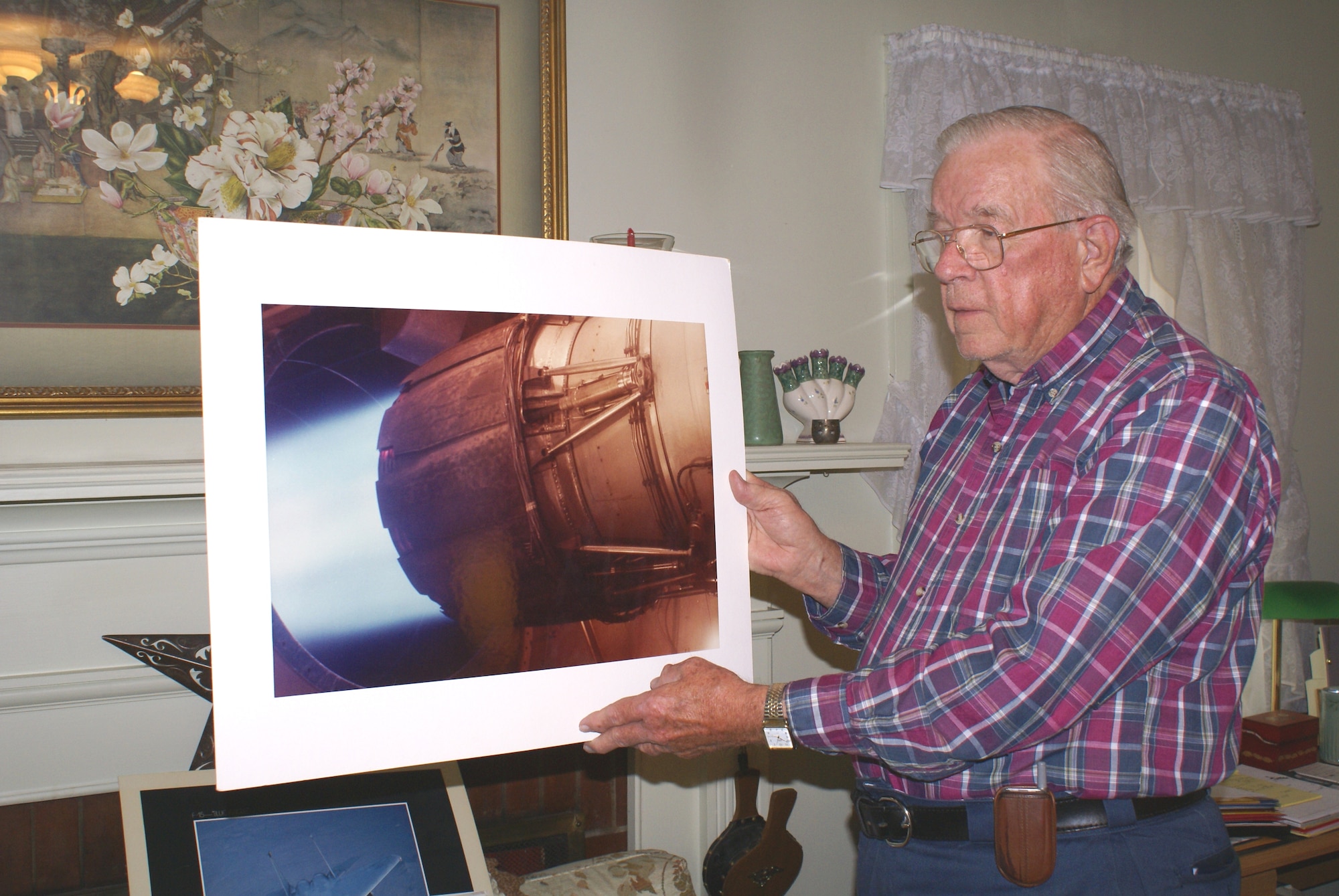 Bob Ansley, an engineer who spent 32 years at Arnold Engineering Development Center, Arnold Air Force Base, Tenn., looks at a photo of the General Electric F101 jet engine, the power plant for the B-1B Lancer bomber, being tested in the center’s J-2 altitude development test cell. (Photo by Philip Lorenz)