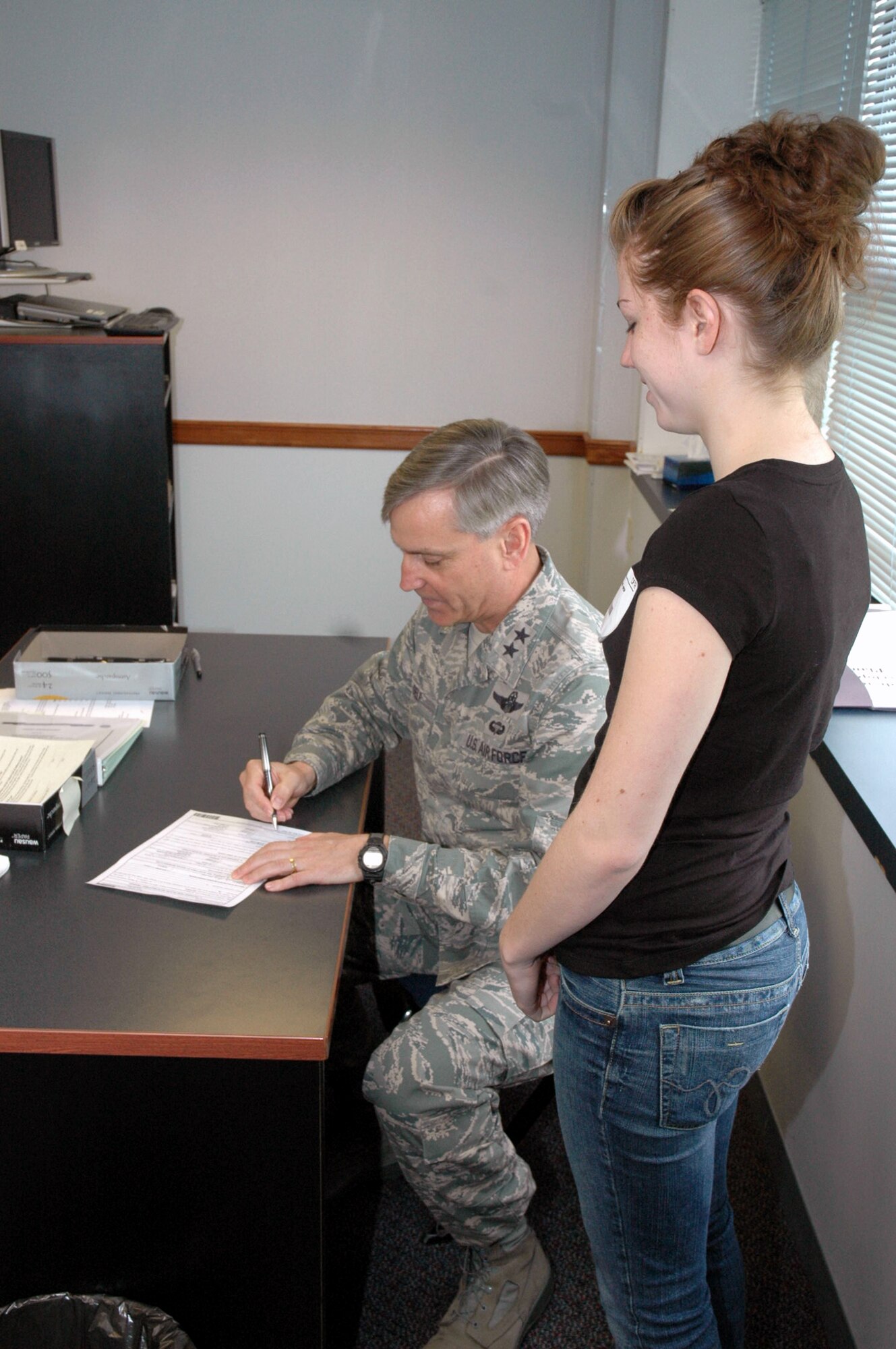 Maj. Gen. Kip Self, U.S. Air Force Expeditionary Center commander, signs enlistment paperwork for Nicole Kazimer after she completed the oath of enlistment along with four other new Air Force enlistees at the Fort Dix Military Entrance Processing Station April 29, 2008, on Fort Dix, N.J.  General Self took the opportunity to do the enlistment oath because Ms. Kazimer is the daughter of Master Sgt. Joe Kazimer of the Center's 421st Combat Training Squadron and Tech. Sgt. Karyn Kazimer of the 108th Air Refueling Wing, McGuire Air Force Base, N.J.  (U.S. Air Force Photo/Tech. Sgt. Scott T. Sturkol)
