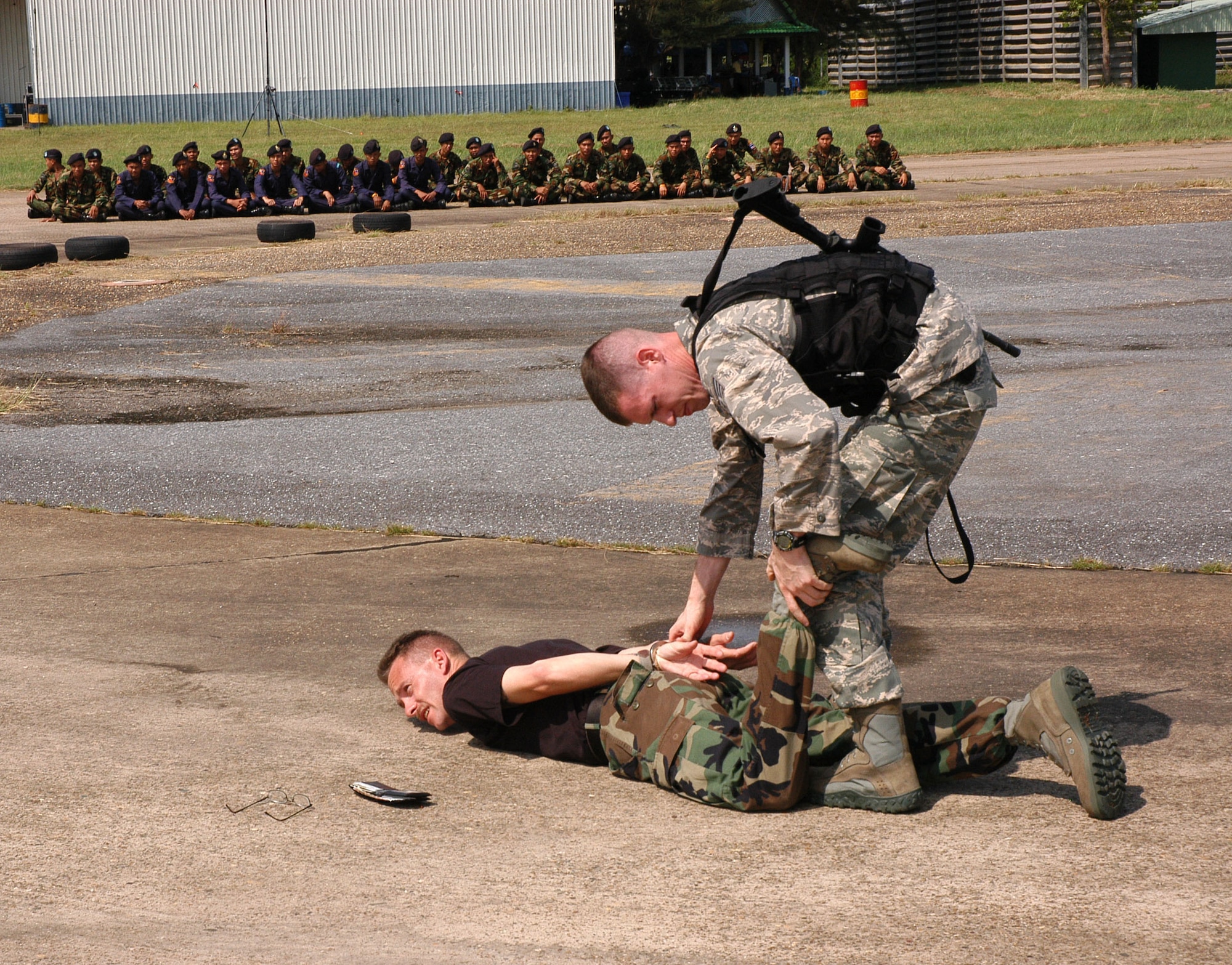 Staff Sgt. Richard Holder, 18th Security Forces Squadron, cuffs Tech. Sgt. Gregory Stout, 353rd Special Operations Group security forces, during exchange training with ground defense forces from Udon Thani, Thailand (in background). (U.S. Air Force photo/Master Sgt. Marilyn Holliday)                        