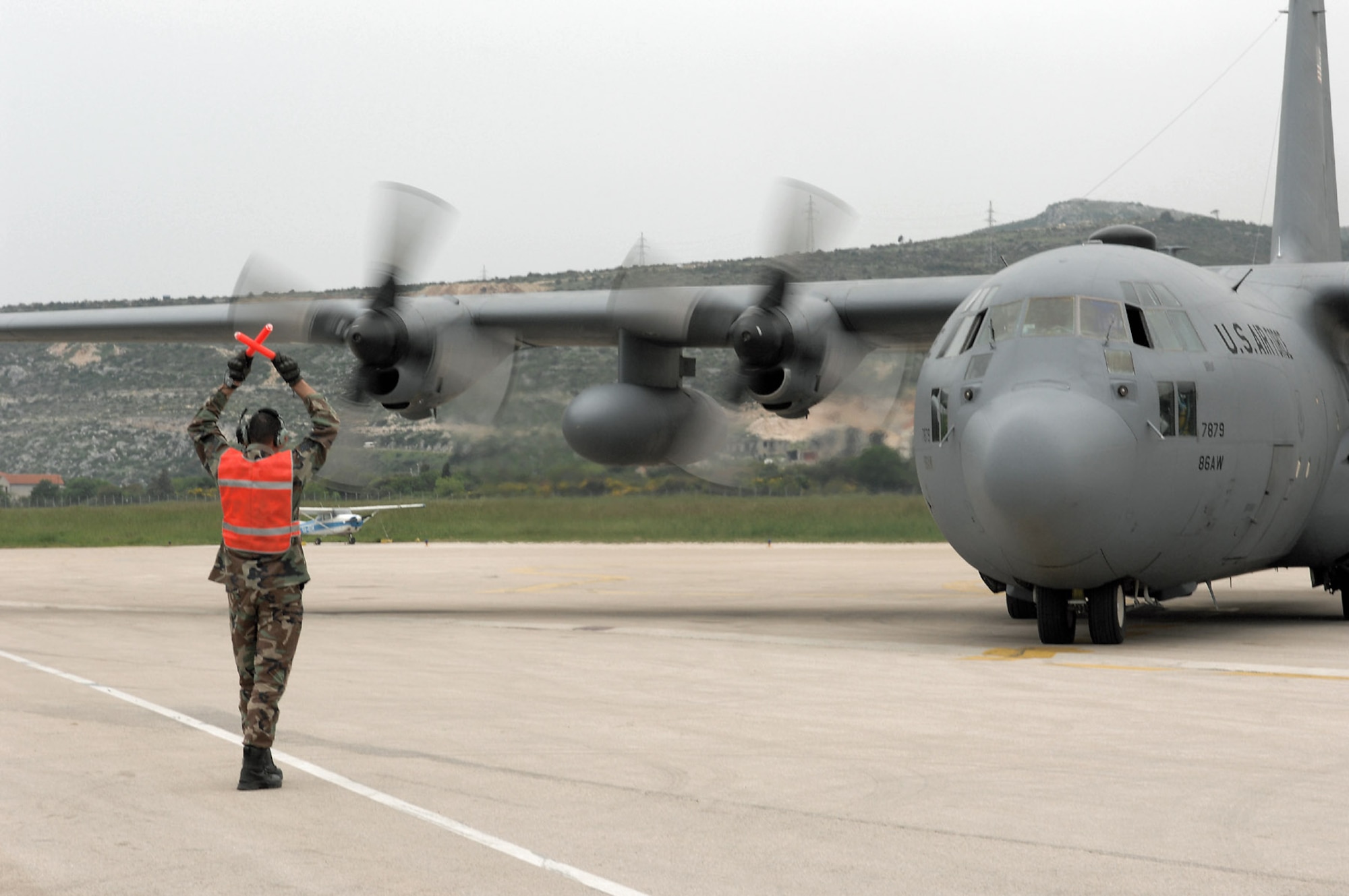 Staff Sgt. Nicholas Panchero marshals in a C-130 Hercules at Divulje Training Base, Croatia, April 29 during the Medical Central and Eastern Europe Exercise 2008. Seventeen nations are participating in the exercise May 2 through 15. The exercise focuses on mass-casualty training scenarios and humanitarian aid in response to crises situations. More than 400 multi-nationals are attending the exercise in support of the Partnership for Peace initiative. Sergeant Panchero is with the contingency response group from Ramstein Air Base, Germany. (U.S. Air Force photo/Staff Sgt. Kristin Ruleau)