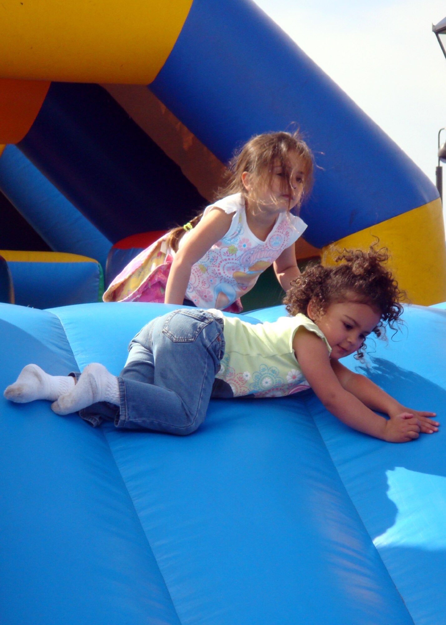 Emilia and Eliza Guadalup tumble down a slide together at the Military Child Fair April 26 at RAF Lakenheath, England. Liberty Airmen and their families were invited to celebrate military children during the fair at the Lakenheath Youth Center. Activites included face painting, a rock wall, bouncy castles and arts and crafts. (U.S. Air Force photo by Airman 1st Class Torri Ingalsbe)