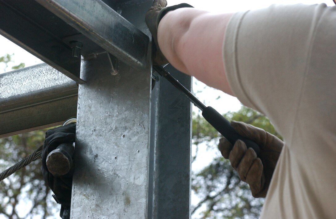 LAS MESAS, HON - Spc. Elizabeth Kurth (right) and Pvt. Aaron Stephens, both of the 322nd Engineer Company, Decorah, Iowa, attach a tension cable to the steel framework of a new storage shed that they are building here April 16. Photo by Staff Sgt. Danny McCormick, Beyond the Horizon public affairs.