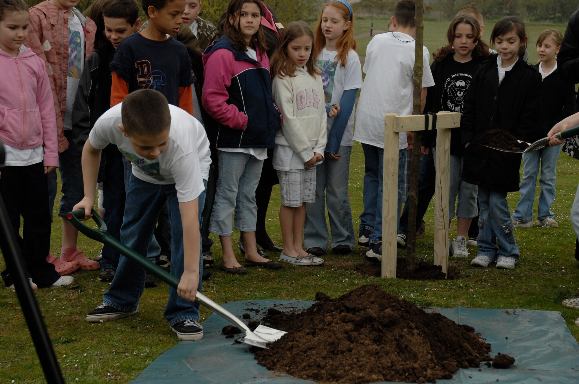Students gather while Ryler Sturm, a member of the Lakenheath Intermediate School student council, shovels dirt to help plant a British Bird Cherry tree in support of Earth Week, April 23 at RAF Lakenheath, England. "Small Changes--Big Differences" is RAF Lakenheath and RAF Mildenhall's motto for Earth Week which runs until April 26. (U.S. Air Force photo by Airman 1st Class Erika Brooke) 