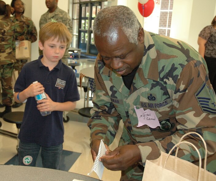 Master Sgt. Stanley Coleman, 94th Airlift Wing public affairs, takes time to sign an autograph for one of the many second graders attending Mount Paran Christian School's military breakfast April 23.  The children, along with help from their teachers, coordinated the annual service event.  The children decorated brown paper bags and filled them with treats for the dozen Airmen who attended.