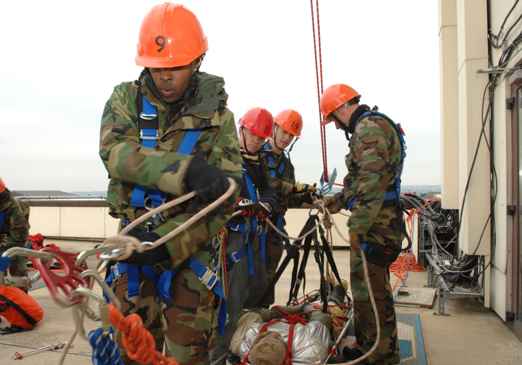 SPANGDAHLEM AIR BASE, Germany-- Airman First Class Martel Hunt, Herr Siegfried Mertiniet, Airman Jason Smith and Herr Gerd Mueller, 52nd Fire and Emergency Services Flight hook a simulated victim on a litter to a rope designed to lower it to safety as part a High Angle Rescue exercise April 18, 2008. The exercise is part of Rescue Technician Level 1 training that several of the firefighters received to enhance their ability to respond to emergencies. U.S. Air Force photo by Senior Airman Logan A. Tuttle. (Released)