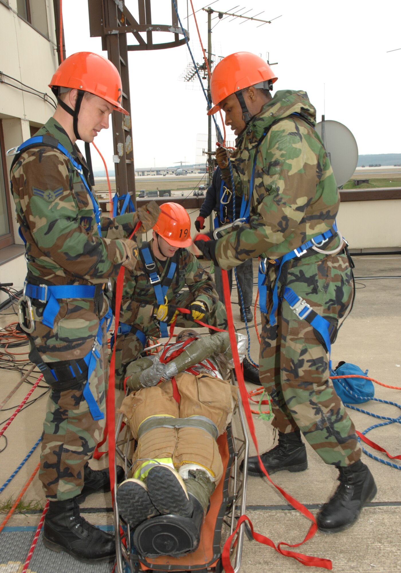 SPANGDAHLEM AIR BASE, Germany-- Airman First Class John Wright, Airman Jason Smith and Airman First Class Martel Hunt, 52nd Fire and Emergency Services Flight strap a simulated victim to a litter as part of a High Angle Rescue exercise April 18, 2008. The exercise is part of Rescue Technician Level 1 training that several of the firefighters received to enhance their ability to respond to emergencies. U.S. Air Force photo by Senior Airman Logan A. Tuttle. (Released)