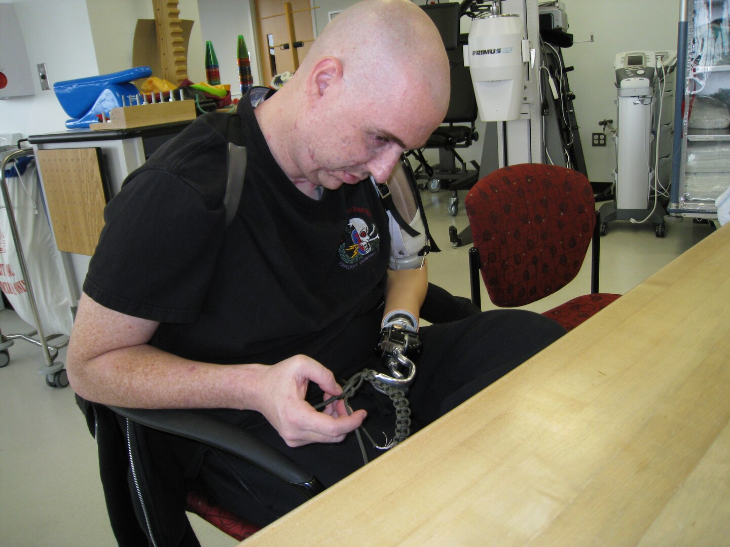 Staff Sgt. Matthew Slaydon works to tie a know with his prosthetic arm during rehabilitation at Brooke Army Medical Center. (Courtesy photo)