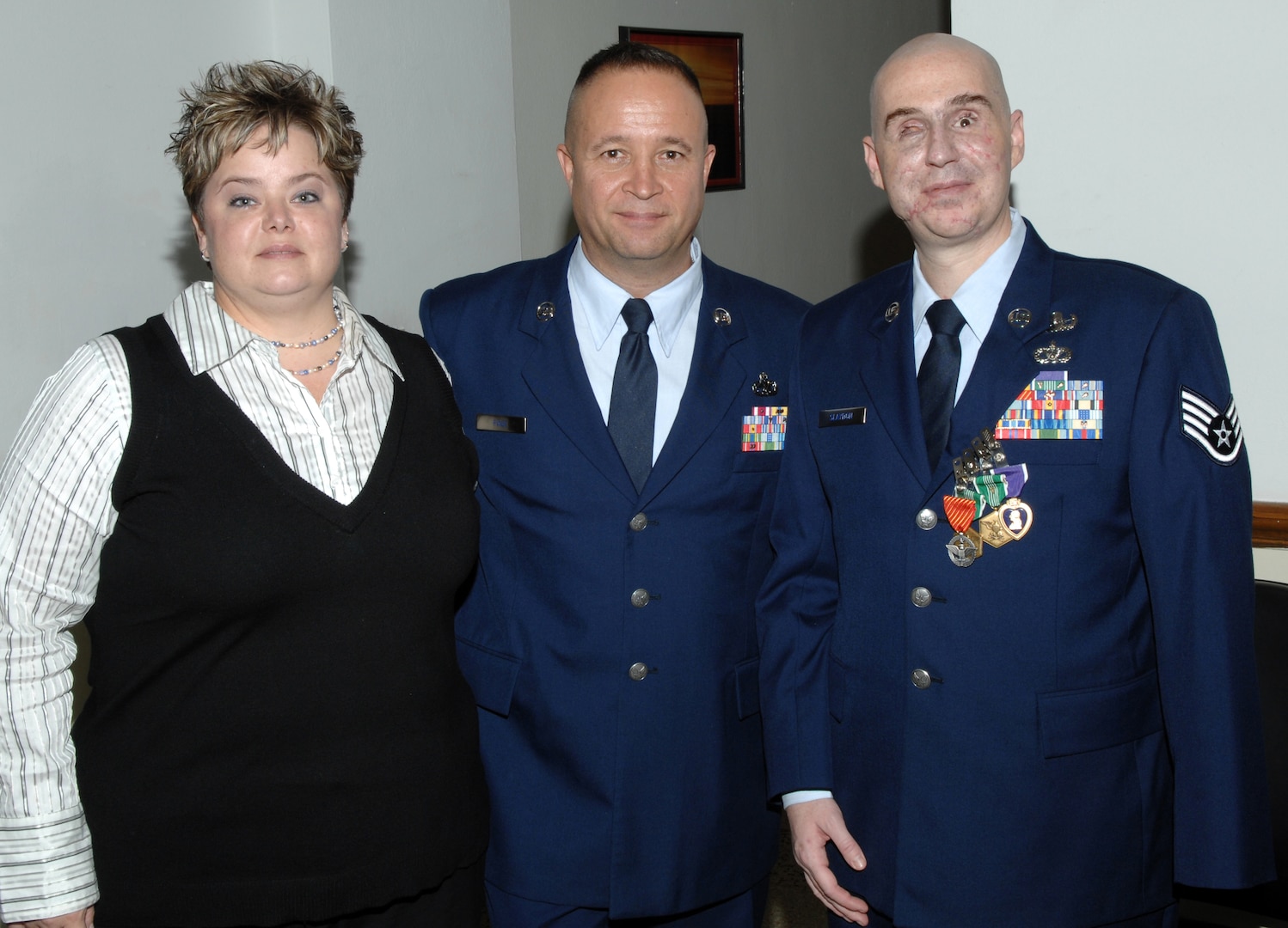 Sergeant Slaydon's wife, Annette, Chief Master Sgt. Stephen Page, 12th Flying Training Wing command chief, and Staff Sgt. Matthew Slaydon pose for a photo at Sergeant Slaydon's Purple Heart Ceremony January 29 at the base theater.