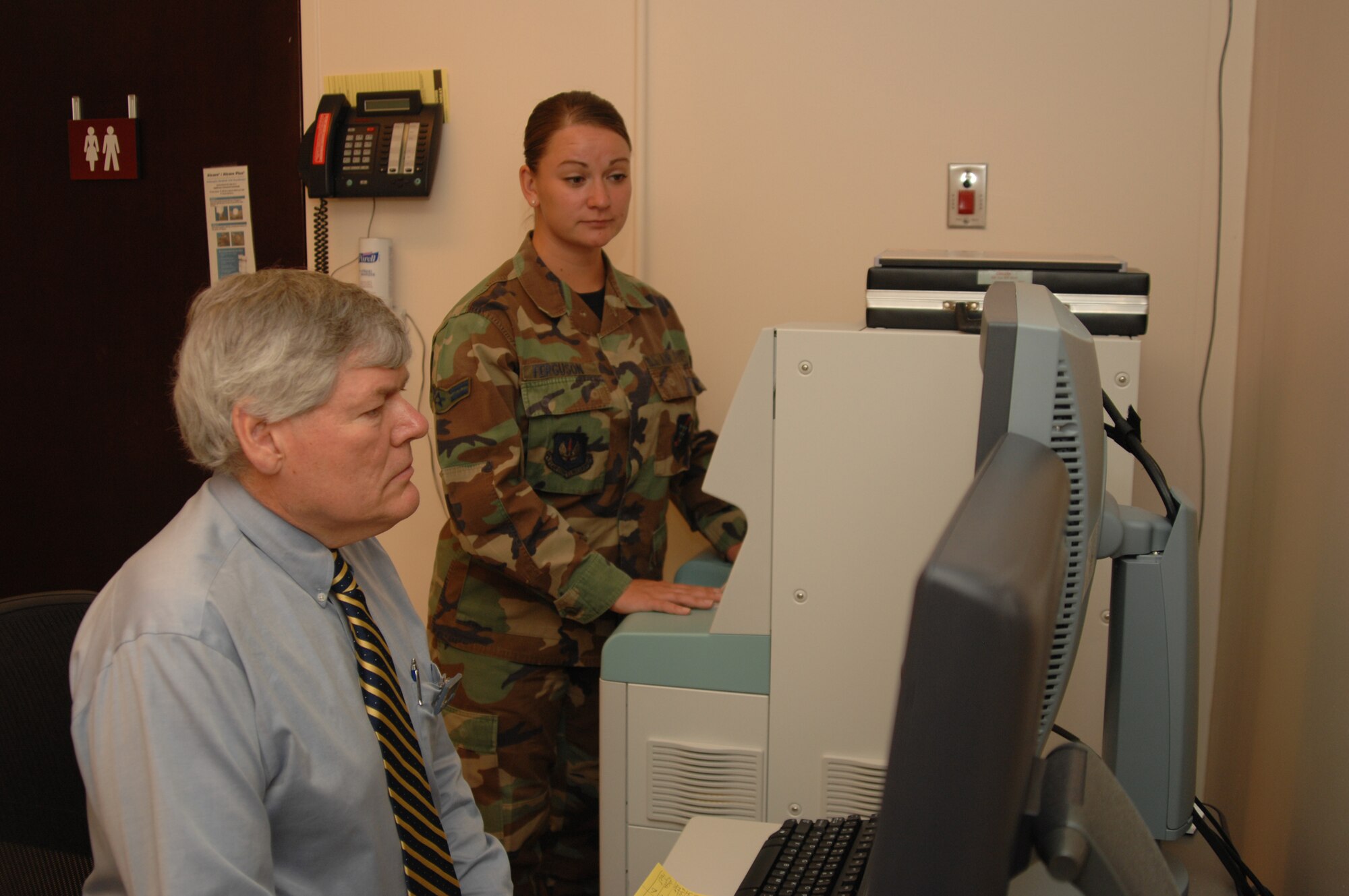 Mr. Terry Bolen of the Food and Drug Administration observes Airman 1st Class Katherine Ferguson, 39th Medical Support Squadron, during an annual inspection at the Incirlik mammography department. The annual inspection ensures the mammography office's machine meets FDA standards, as well as ensuring the technician adheres to those standards. (U.S. Air Force photo by Senior Airman Lauren Padden)