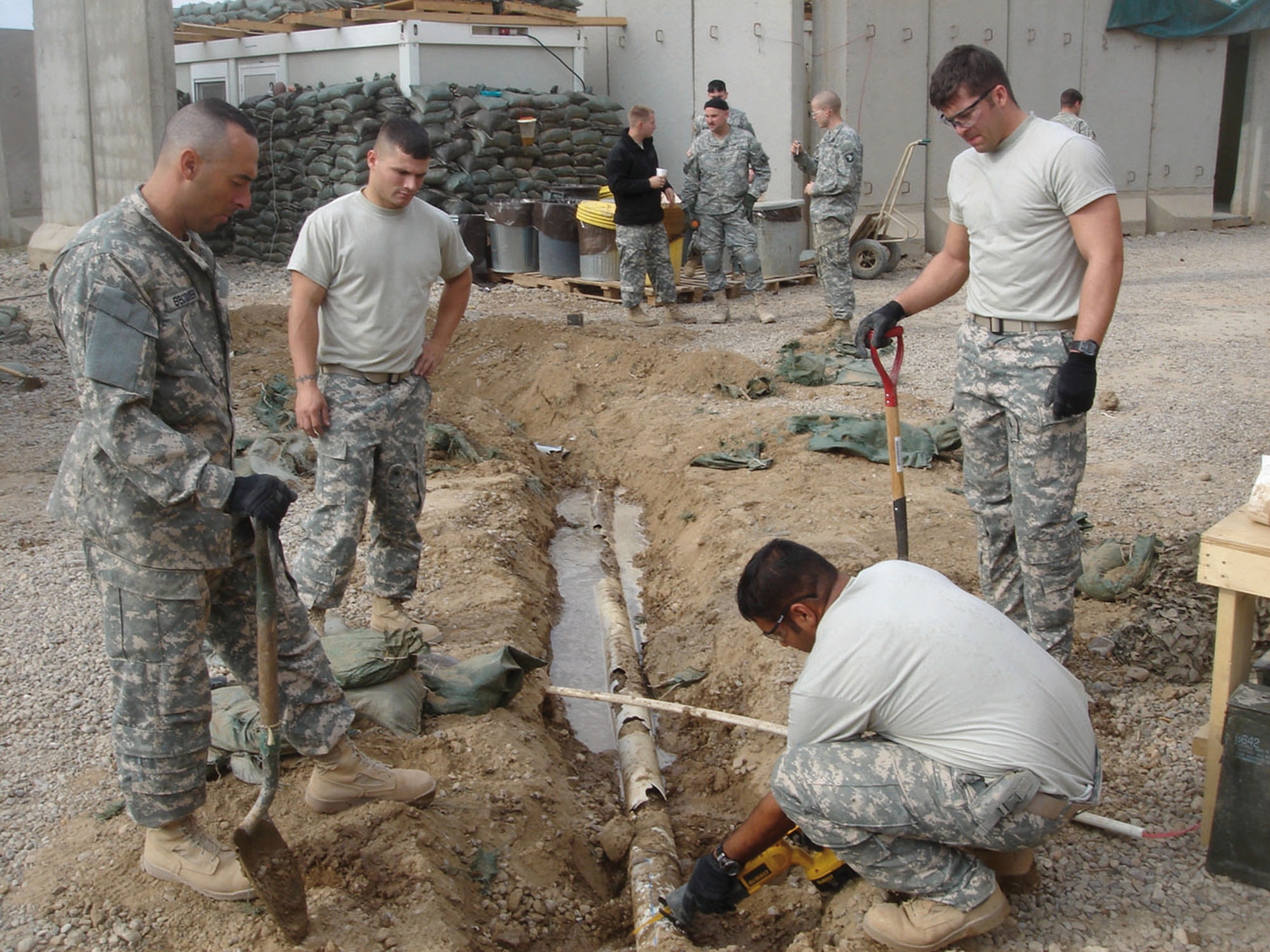 (From left) Tech. Sgt. John Becquer, Airman 1st Class Matthew Giacona and Staff Sgt. Caleb Dennis, all from the 732nd Expeditionary Civil Engineer Squadron Detachment 6, watch as Staff Sgt. Pranay Singh, a utilities craftsman also with Det. 6, cuts through a drain pipe. The pipe will carry  water to the showers, clothes washers and kitchen at Patrol Base Olson, Iraq. The Airmen are assigned to the 18th Civil Engineer Squadron here. (U.S. Air Force photo)

