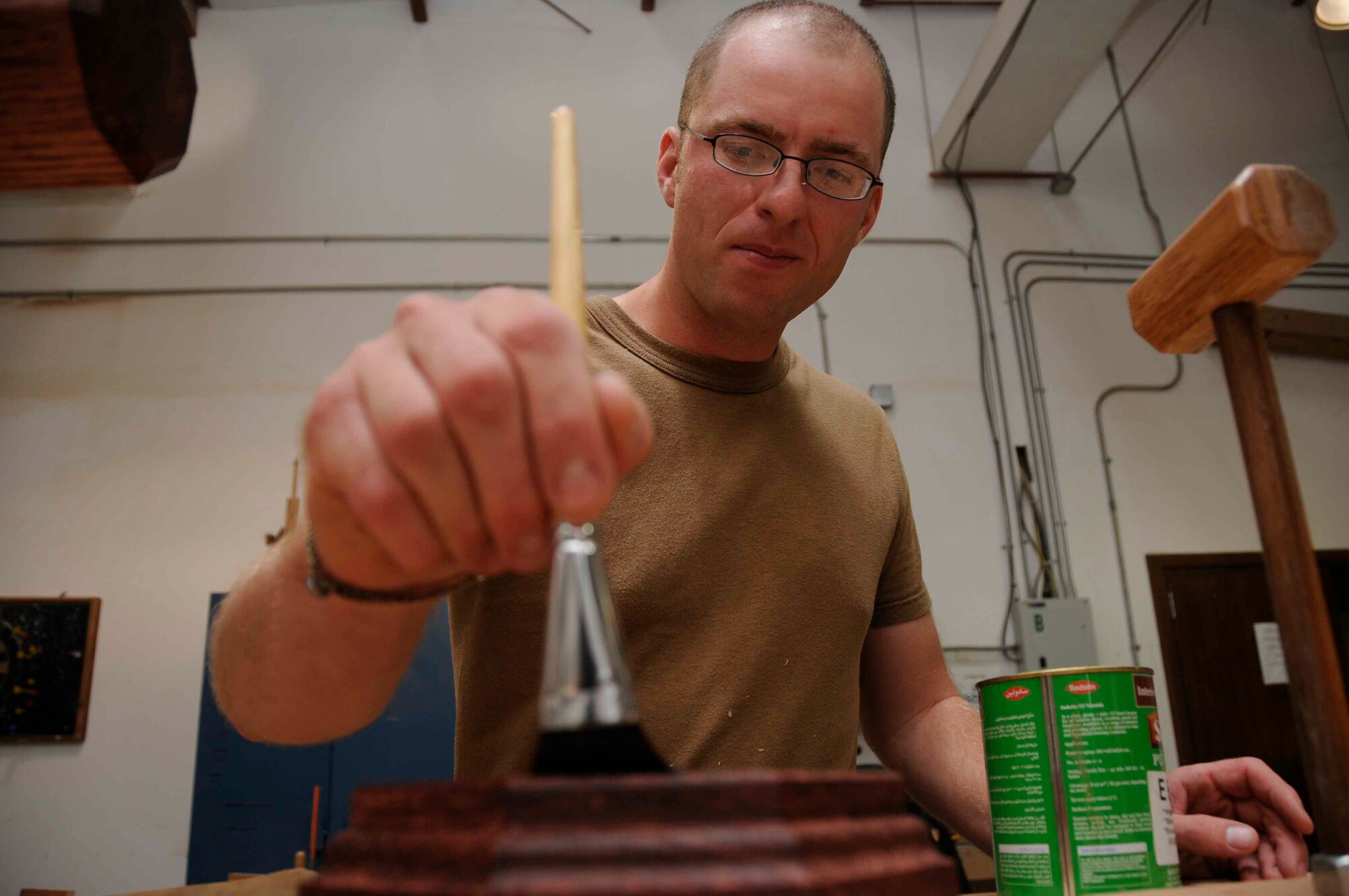 SOUTHWEST ASIA—Staff. Sgt. Jessie Butikofer, 379th Expeditionary Civil Engineer structures specialist, glazes a gavel block April 30.  The gavel and block combination is to be used for an upcoming Combat Dining Out. (U.S. Air Force photo/Senior Airman Domonique Simmons)
