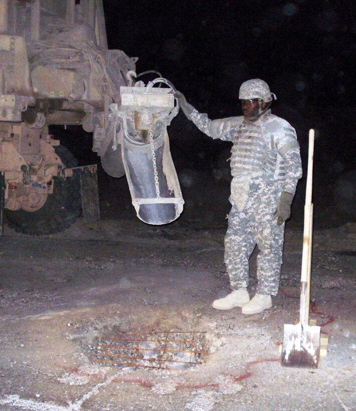 Army Sgt. James Bridges, from Gulfport, Miss., sets the spout of his concrete mobile truck over a crater before pouring concrete while performing rapid crater repair in northwestern Baghdad. U.S. Army photo by Sgt. Henry Bauer, Multinational Division Baghdad