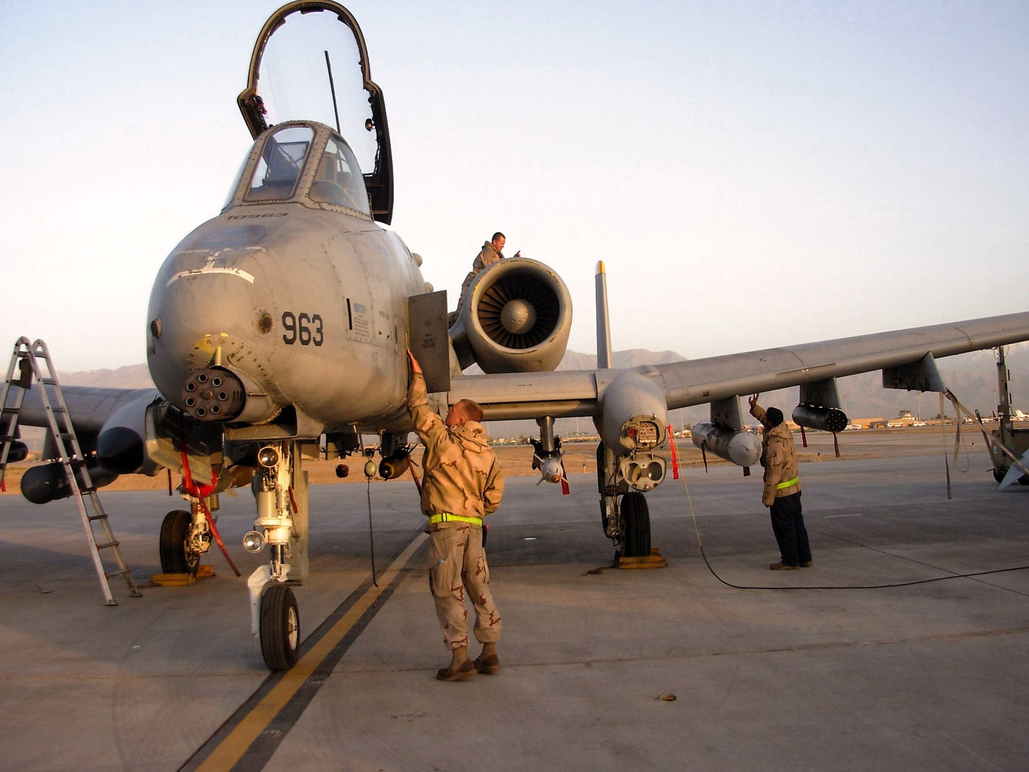 Senior Airman Justin Lovejoy inspects the fuselage of an A-10 Thunderbolt II at Bagram Air Base, Afghanistan, while Staff Sgt. Isaac Ibarra inspects the wing during a thru-flight inspection.  Up on one of the two engines, Staff Sgt. Shawn Mercier pulls an oil sample. The crew chiefs, assigned to the 81st Expeditionary Aircraft Maintenance Unit, are deployed from Spangdahlem Air Base, Germany. (U.S. Air Force photo by Master Sgt. Tom Bivens)