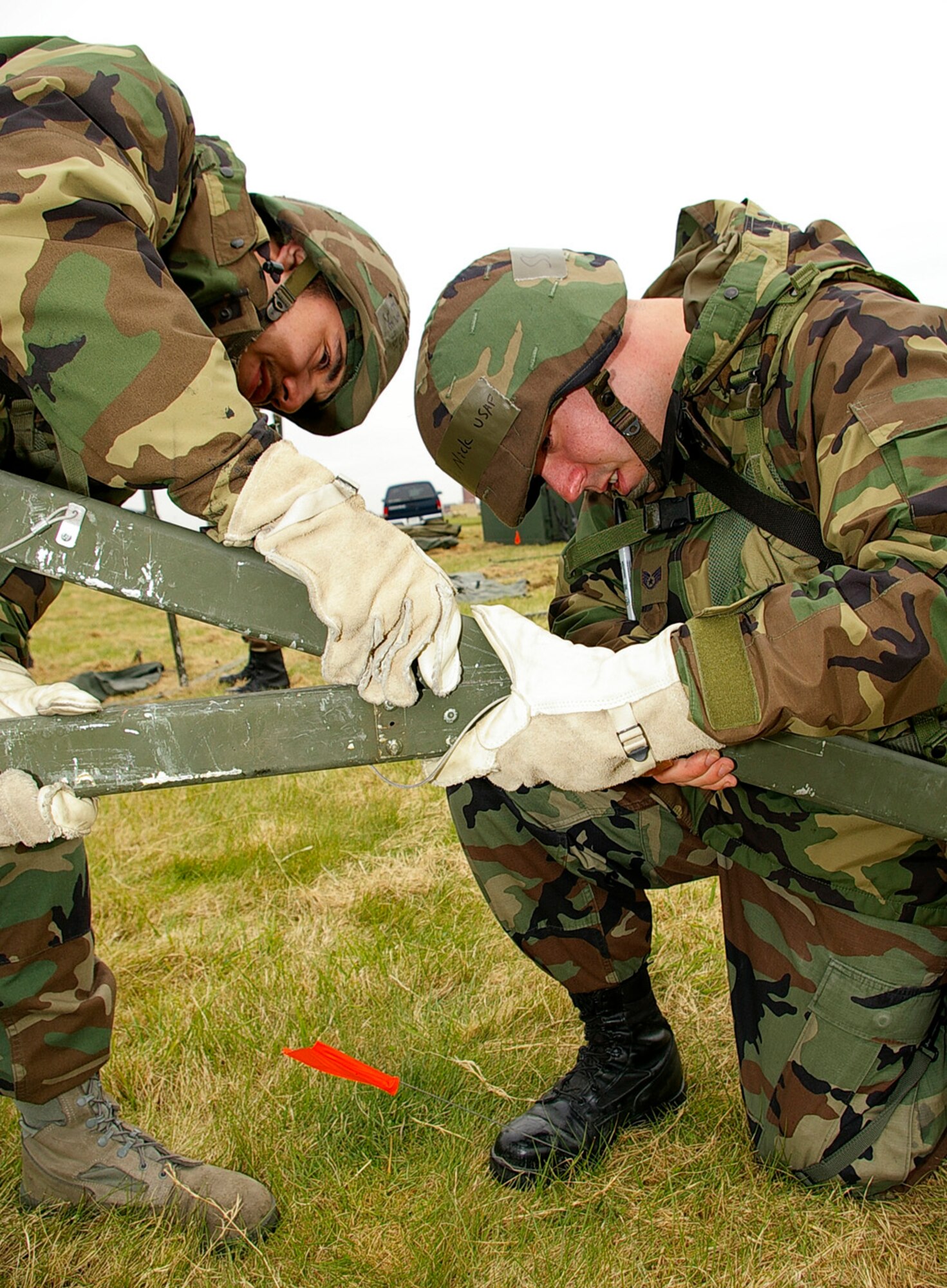 Airman 1st Class Justin Santamaria, left, and Staff Sgt. Nick Malard, both 100th Civil Engineer Squadron, work together to connect a tent frame during civil engineering's field training exercise April April 24. (U.S. Air Force photo by Karen Abeyasekere)