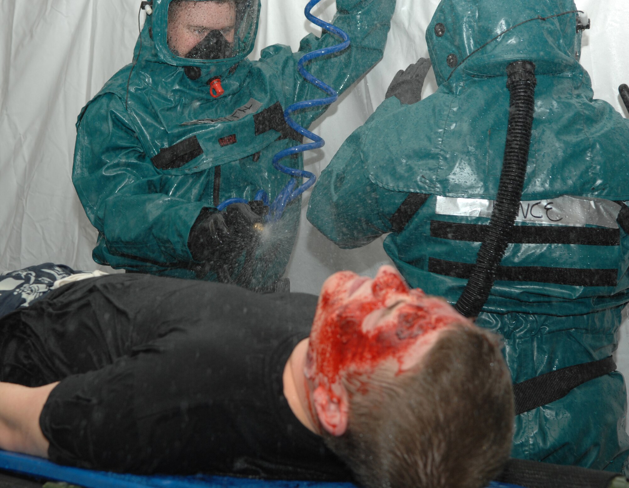 A1C Jared Smith and SSgt Carl Pence processed moulage patients, like A1C Jacob Abplanalp, through a decontamination tent as part of exercise Saber Crown 08-06 at Spangdahlem AB, Germany, on April 23, 2008. (U.S. Air Force Photo/Staff Sergeant Heather M. Norris)