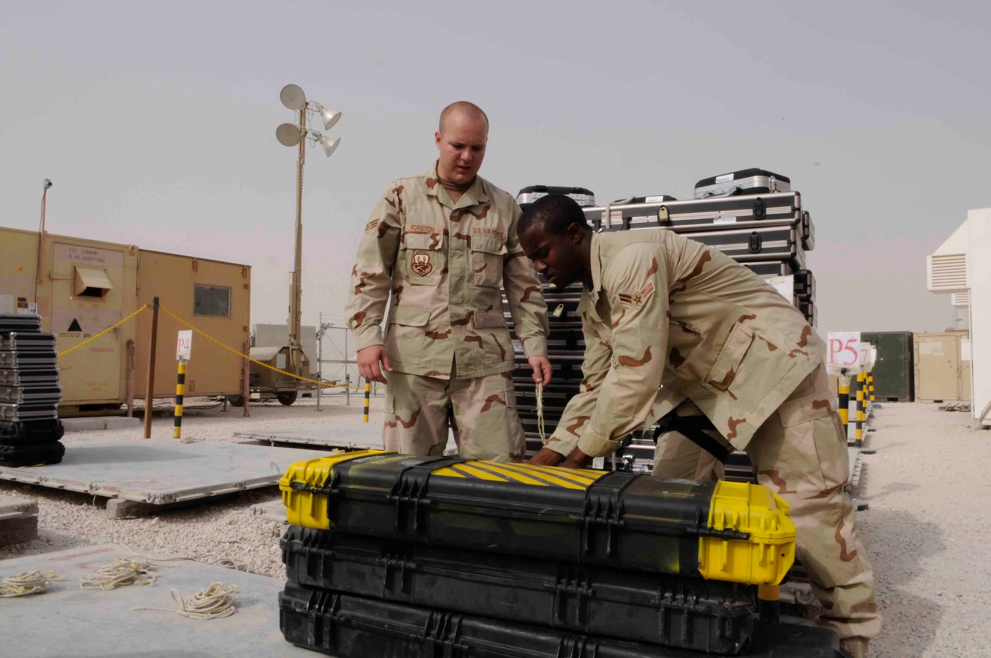 Senior Airman David Fortson and Airman 1st Class Chad Bailey prepare to secure weapons onto pallets at the ammunition storage facility here. They secure and store weapons for more than 10,000 deployed members each month. (Photo by Tech. Sgt. Johnny Saldivar)