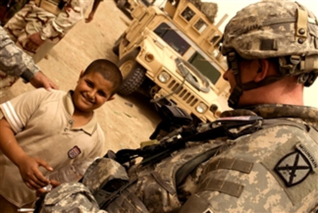 U.S. Army Sgt. Michael Valley speaks with the first of many Iraqi children to arrive during a food distribution mission in the Zuwerijat district of Al Kut, Iraq, April 30, 2008. Valley is assigned to the 511th Military Police Company.

