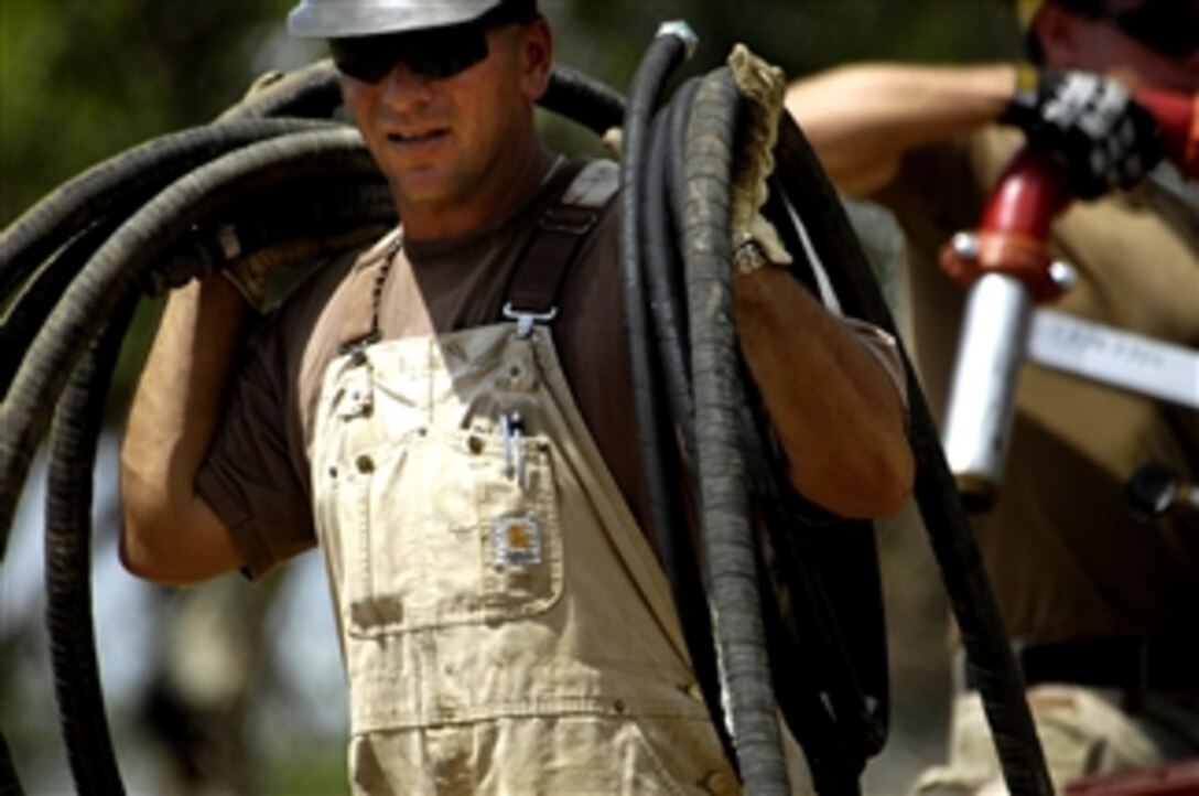 U.S. Navy Equipment Operator Petty Officer 1st Class Steven Barczak, a Seabee from Naval Mobile Construction Battalion 74, Combined Joint Task Force - Horn of Africa, unloads hoses from a truck as other Seabees assemble a rig during a well drilling project in Shaba, Kenya, on April 21, 2008.  The well drilling project was the first of three Seabees conducted in the area.  