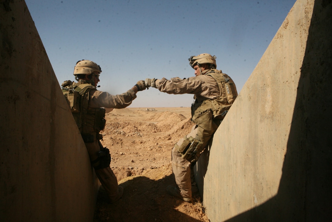 Sgt. Marty S. Crisp, a scout squad leader with Charlie Company, 2nd Light Armored Reconnaissance Battalion, Regimental Combat Team 5, pounds fists with Cpl. Joshua P. Ronan, a scout team leader with Charlie Company, to celebrate after searching through a variety of old Iraqi bunkers in western Anbar province, Iraq, May 2. Marines with Charlie Company, known as 'Gunfighter,' foot patrolled in and around the area, ensuring the bunkers and air fields were clear of ordnance or weapons insurgents use to inflict danger on Coalition forces.