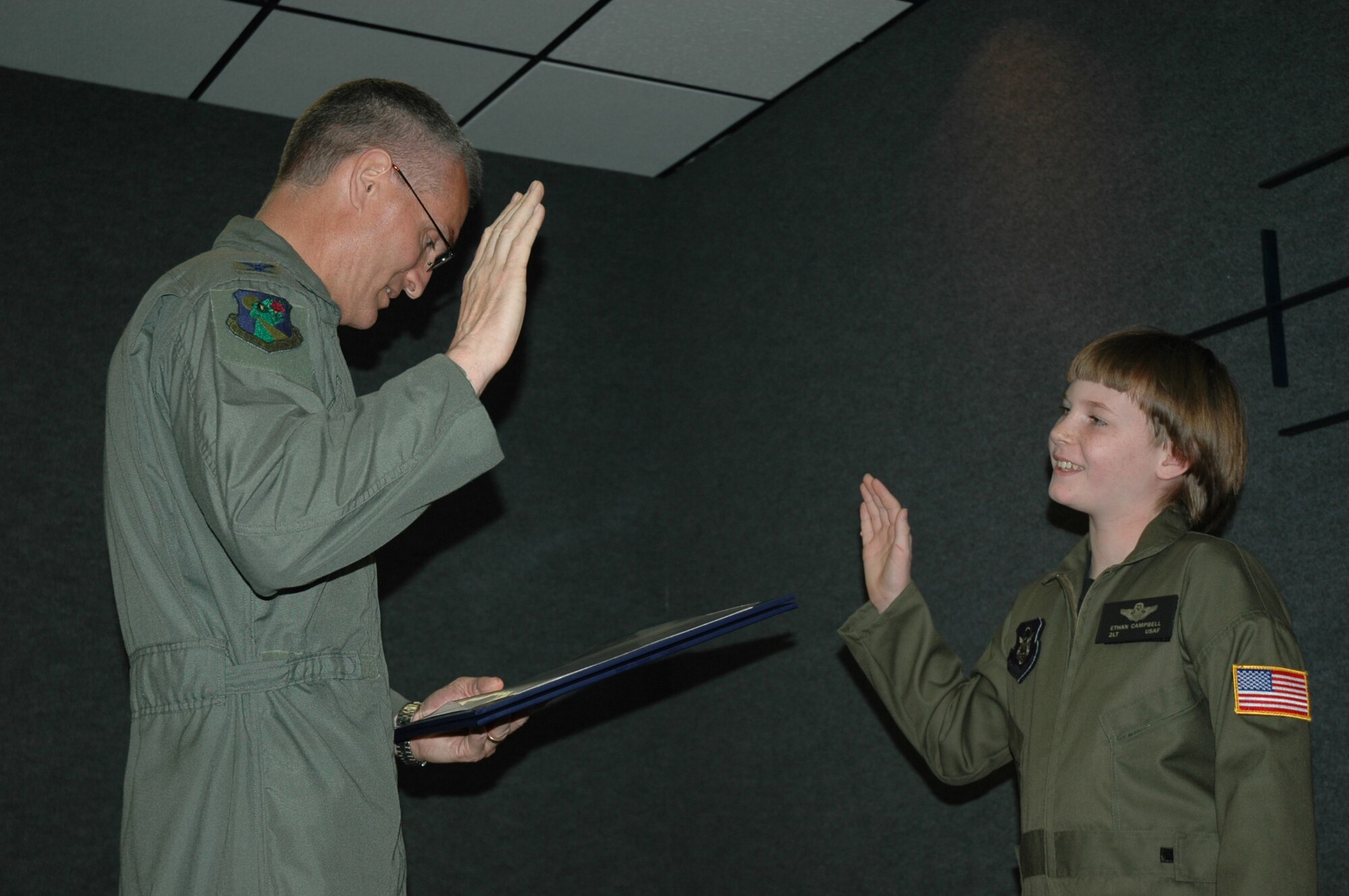 Col. Steven J. Chapman, 919th Special Operations Wing commander, reads soon to be 2nd Lt. Ethan Campbell the Officer's Oath of Office during Pilot for a day May 2. The 10-year-old honorary pilot is diagnosed with leukemia. The Pilot for a Day program gives children with serious health conditions a break from treatments to experience a day in the life of an Air Force pilot. Lieutenant Campbell was treated to an all-star tour of the Duke Field Fire Department, experienced a simulator ride, battled insurgents with security forces members, and taxied down a runway in an MC-130E Combat Talon I aircraft where he was then given his pilot's wings. (U.S. Air Force Photo/Jasmine DeNamur)