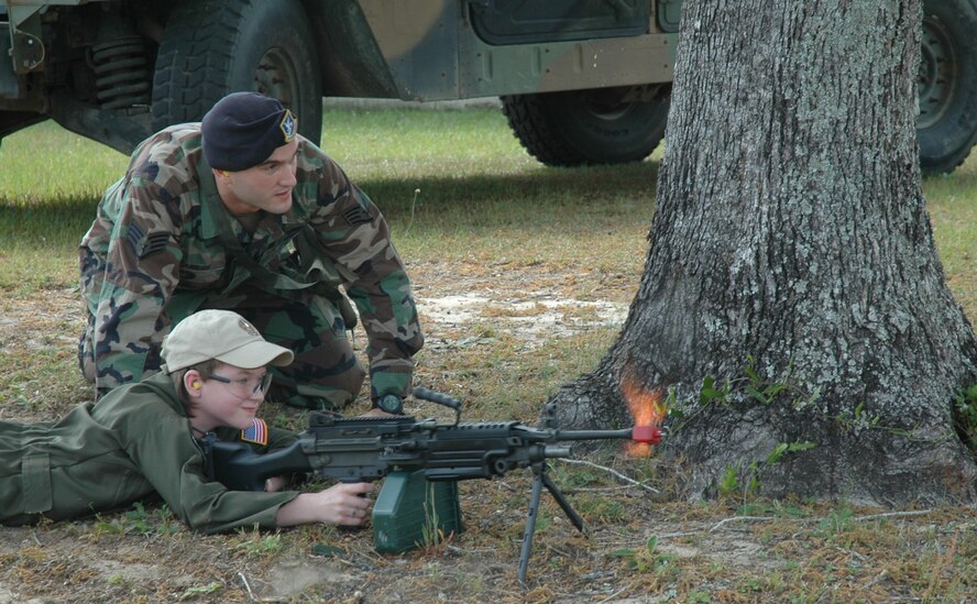 Staff Sgt. James Parrish, 919th Security Force Squadron member, assists 2nd Lt. Ethan Campbell shoot blank fire rounds at "insurgents" during Pilot for a Day at Duke Field May 2. The 10-year-old honorary pilot is diagnosed with leukemia. The Pilot for a Day program gives children with serious health conditions a break from treatments to experience a day in the life of an Air Force pilot. 2nd Lieutenant Campbell was treated to an all-star tour of the Duke Field Fire Department, experienced a simulator ride, battled insurgents with security forces members, and taxied in the wing's aircraft where he was then given his pilot's wings. (U.S. Air Force Photo/Jasmine DeNamur)
