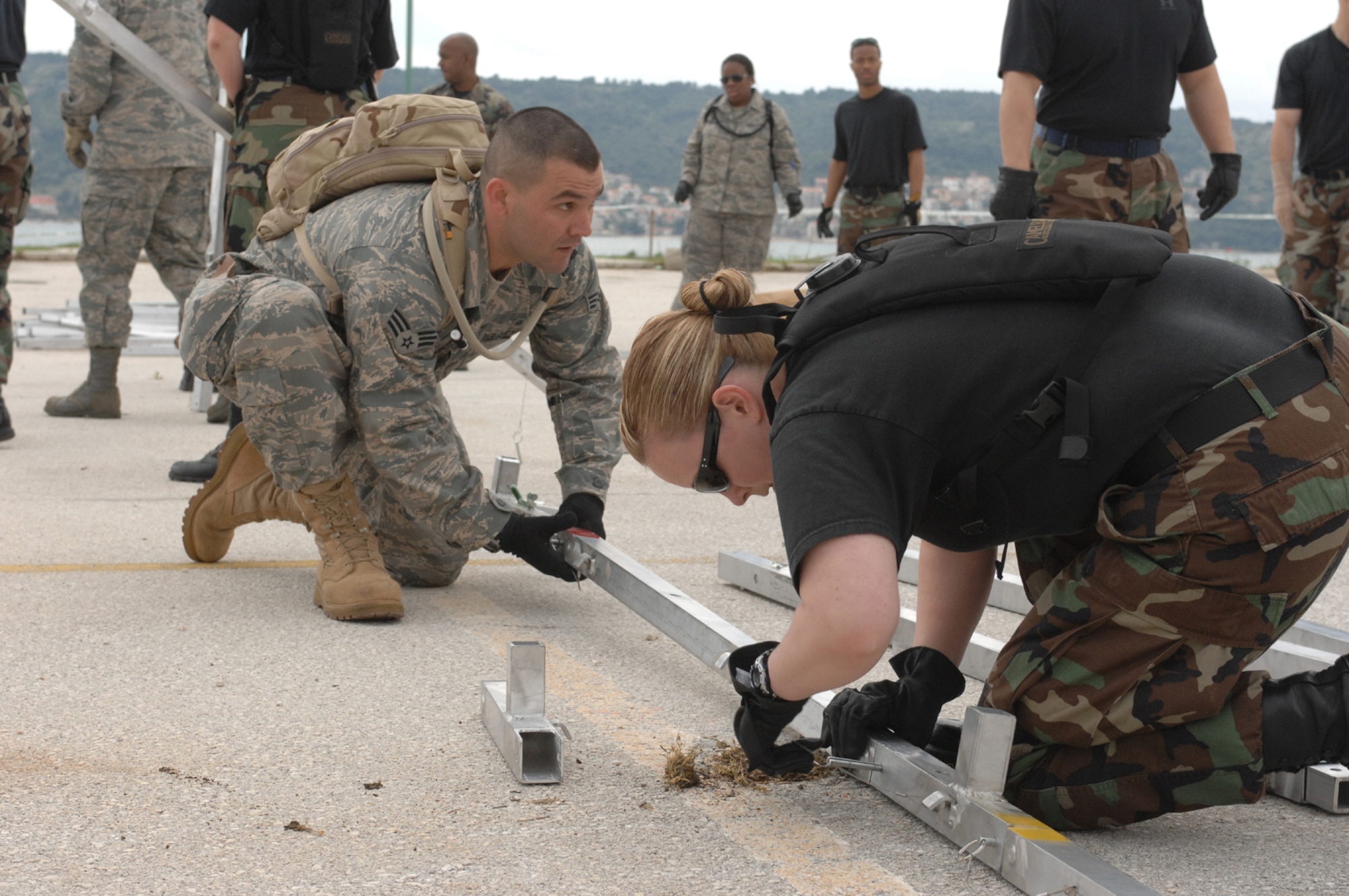 DIVULJE TRAINING BASE, Croatia – U.S. Air Force’s Senior Airman Tim Raso, 52nd Medical Operations Squadron, and Tech. Sgt. Breah Misho, 52nd Aerospace Medicine Squadron, join together to learn how to assemble tents April 30.  The tents are Expeditionary Medical Squadron (EMEDS) +10 tents designed to provide patient care for ten or more people as a mobile field hospital.  Misho and Raso are both deployed from Spangdahlem Air Base, Germany, for the 2008 Medical Training Exercise in Central and Eastern Europe (MEDCEUR).  Fifteen nations are participating in the exercise from May 2 through 14. The exercise focuses on mass-casualty training scenarios and humanitarian aid in response to crises situations. More than 400 multi-nationals are attending the exercise in support of the Partnership for Peace initiative. (U.S. Air Force photo/Staff Sgt. Kristin Ruleau) 